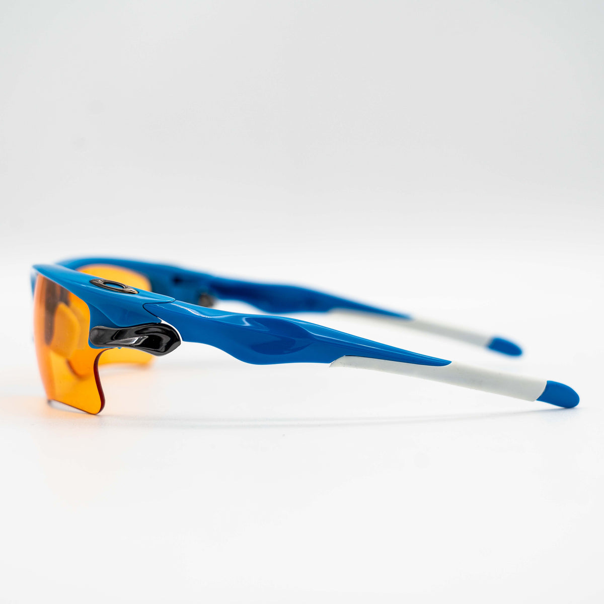 Oakley Fast Jacket OO9156-04 sunglasses in blue with orange lenses, displayed with two extra pairs of lenses, cleaning cloth and a black Oakley hard case.