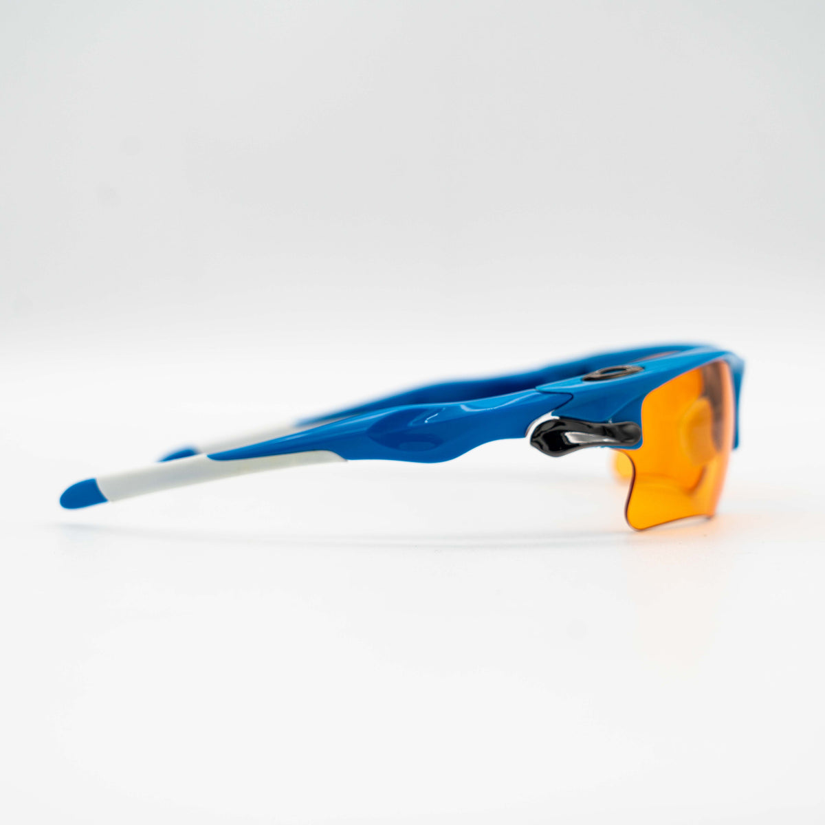Oakley Fast Jacket OO9156-04 sunglasses in blue with orange lenses, displayed with two extra pairs of lenses, cleaning cloth and a black Oakley hard case.