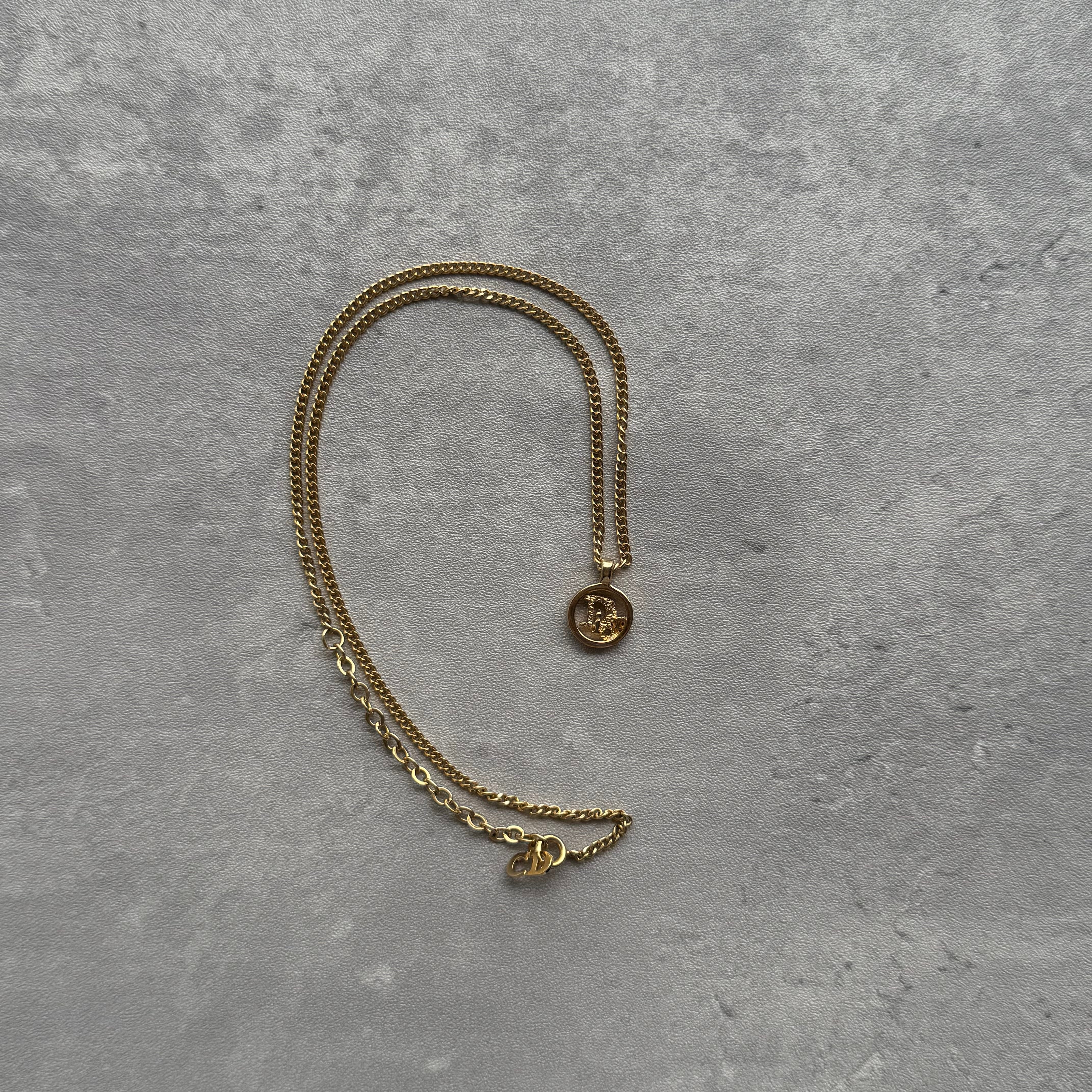 Dior Small Logo Pendant Necklace in gold-plated metal, featuring a tiny circular charm on a slim curb chain.