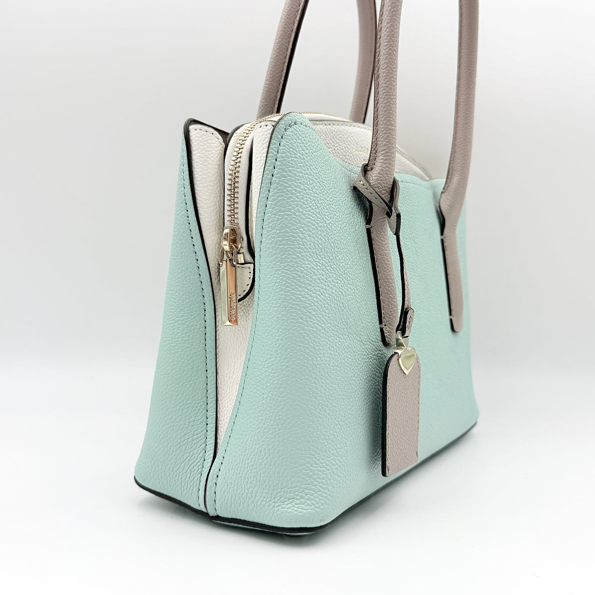 Kate Spade New York Margaux satchel in mint green pebbled leather with taupe handles, shown with its detachable strap and a clear pouch.