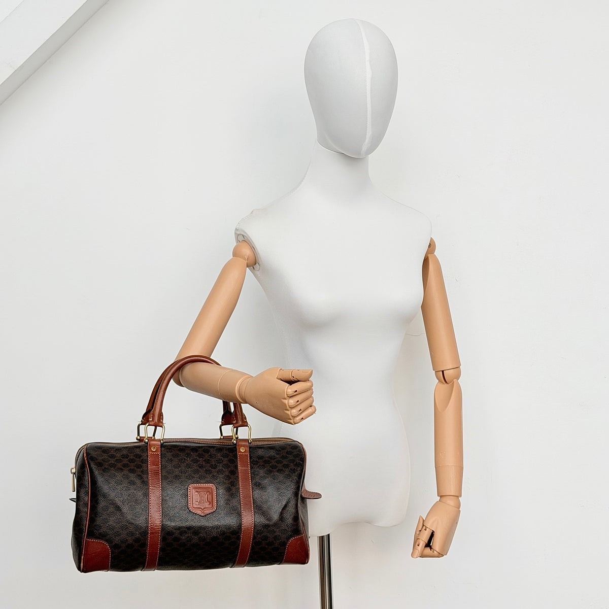Celine Macadam Triomphe Boston Bag in brown coated canvas with tan leather and gold-tone hardware, shown against a white background.