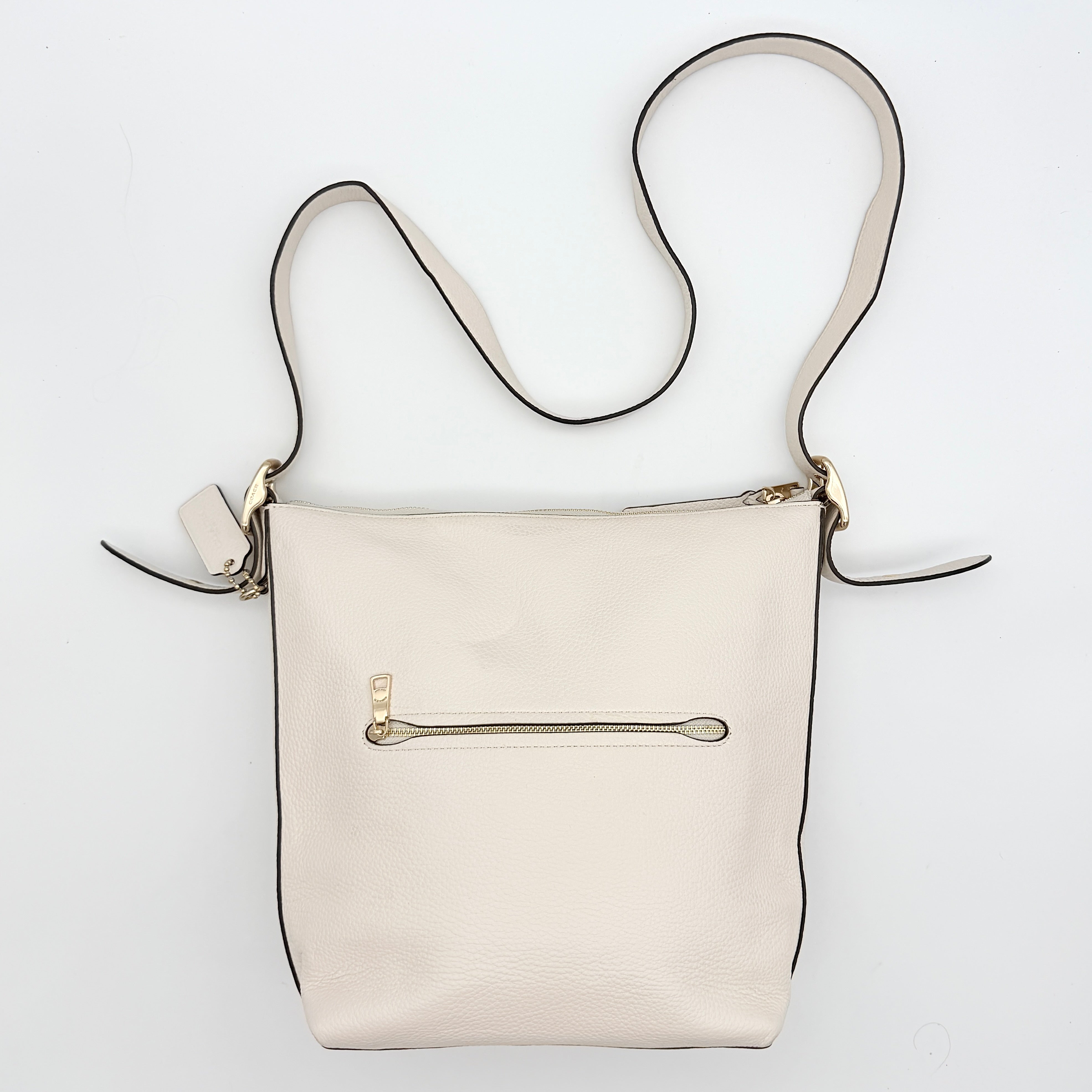 Coach Ellie File Crossbody Bag in ivory pebbled leather with gold hardware and adjustable strap, displayed on a white background.