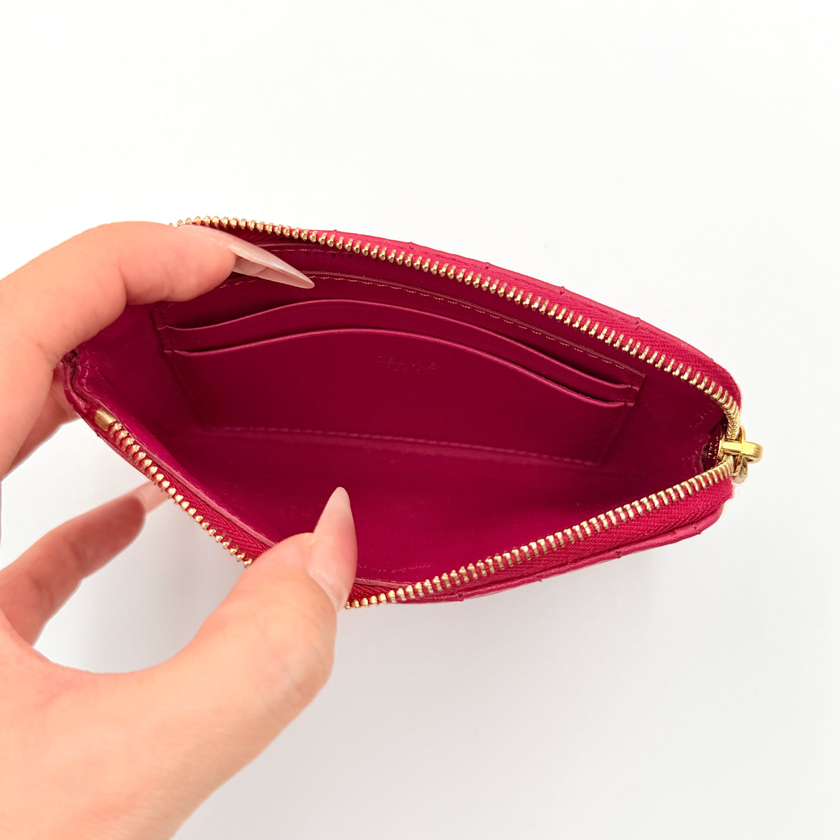 Celine quilted pink coin and card wallet with gold C charm, displayed on a black Celine dust bag.