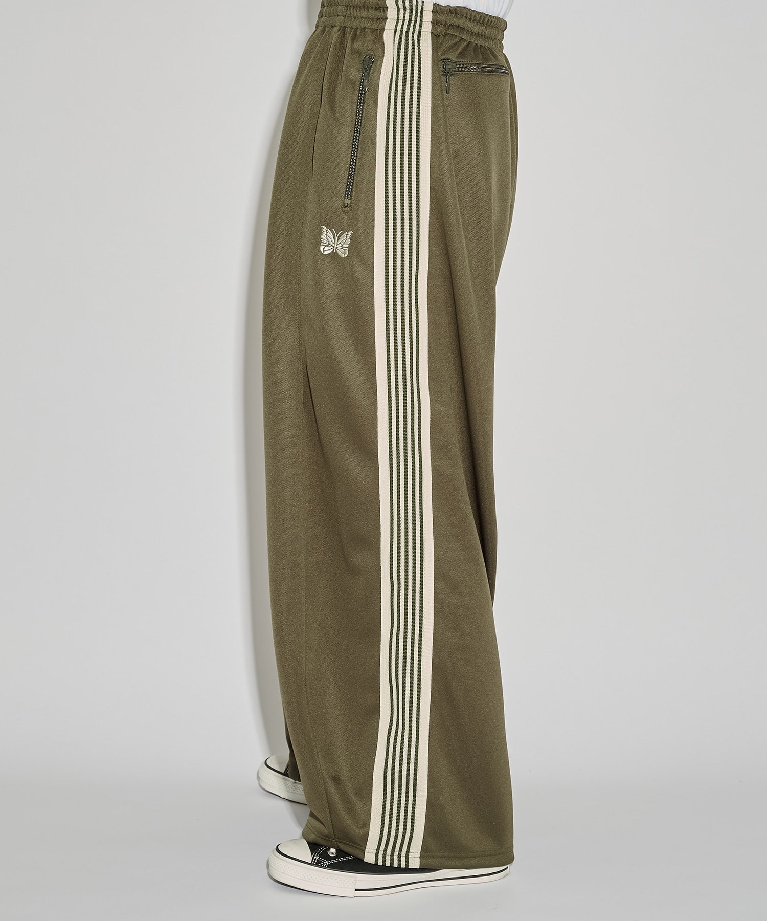 Needles H.D. Track Pant in olive green with cream stripes and butterfly logo, shown in a relaxed silhouette.
