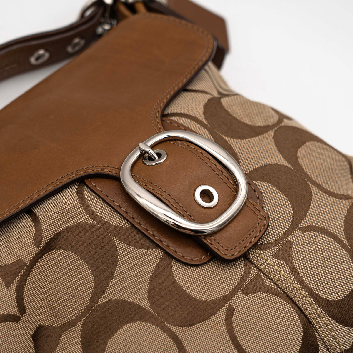 Coach 2Way Signature Soho Buckle Flap Shoulder Bag in beige and tan with silver buckle and adjustable leather strap, shown on a white background.