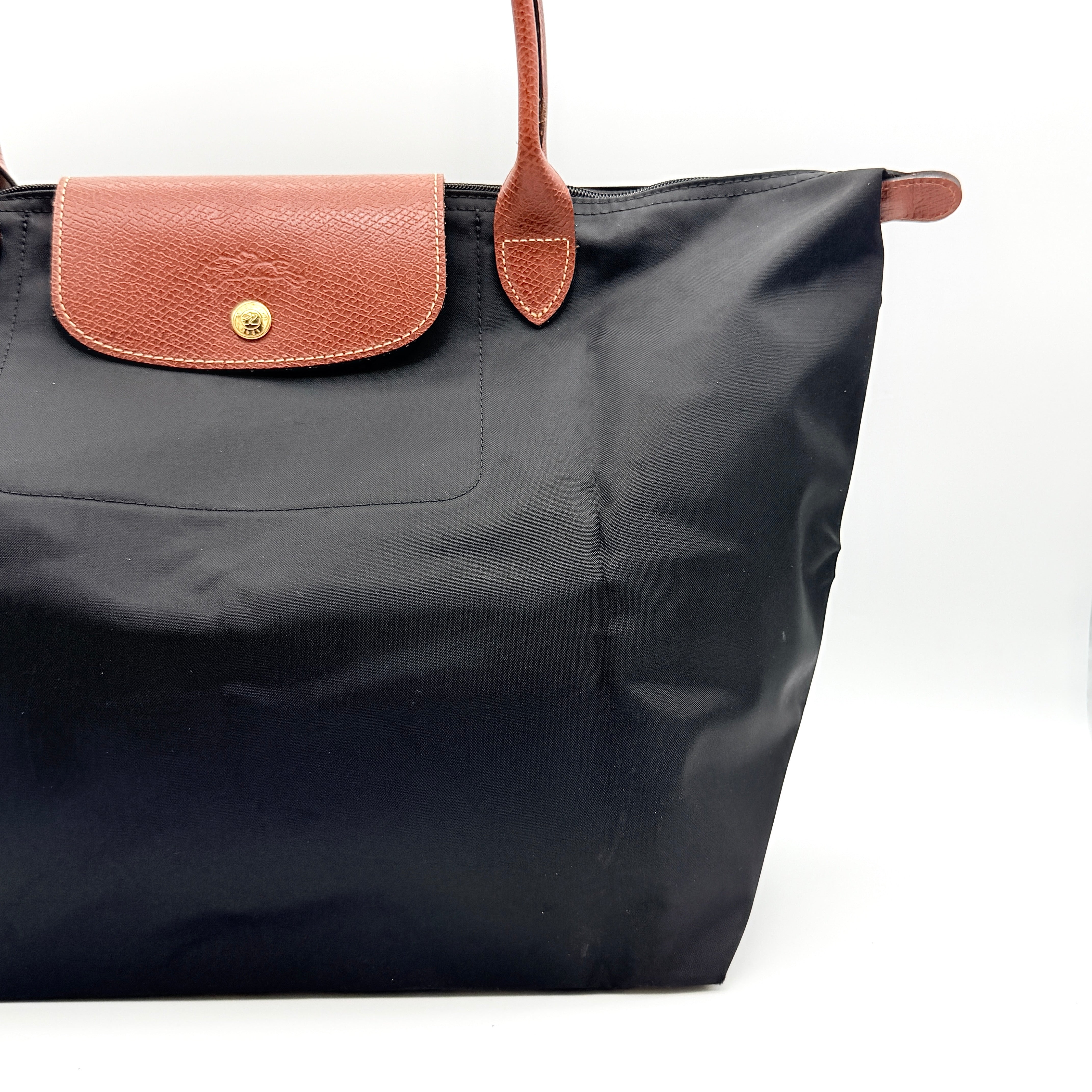 Longchamp Le Pliage Original Tote Bag in black with brown leather handles and flap, photographed against a white background.