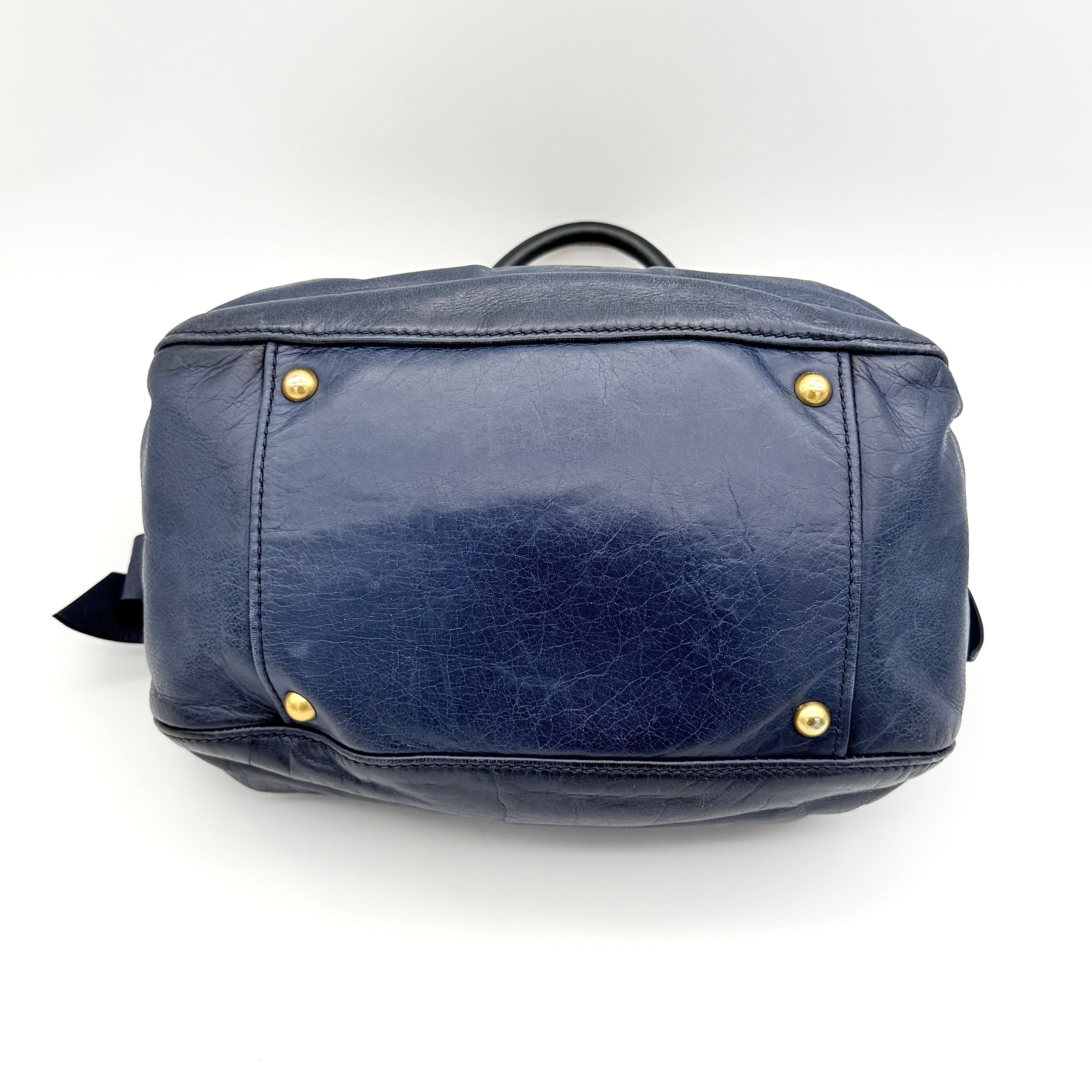 Miu Miu navy blue Vitello Lux Bow Satchel with gold-tone hardware, detachable strap, and dust bag.