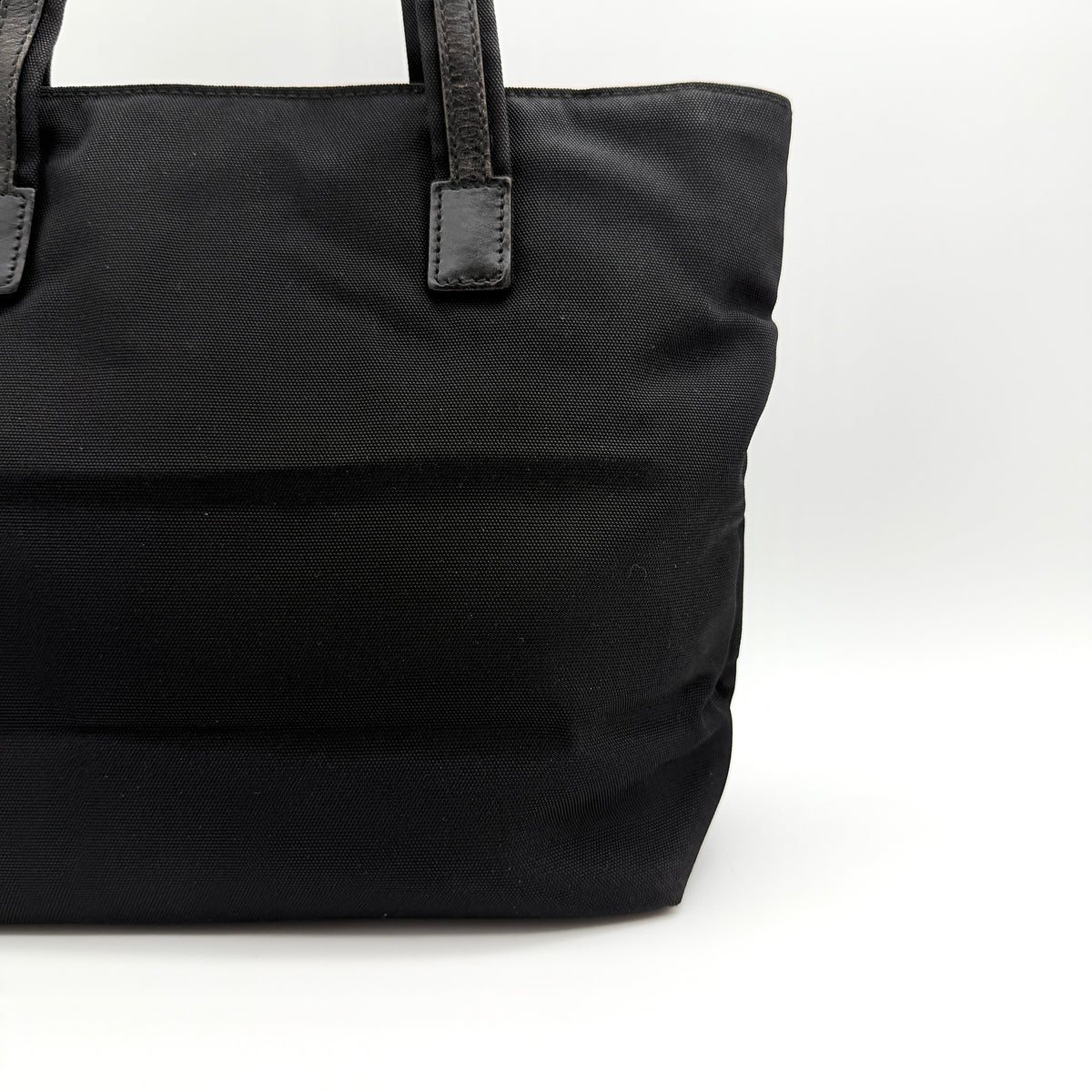 Front view of the Gucci black nylon tote with dual zip pockets and leather top handles.