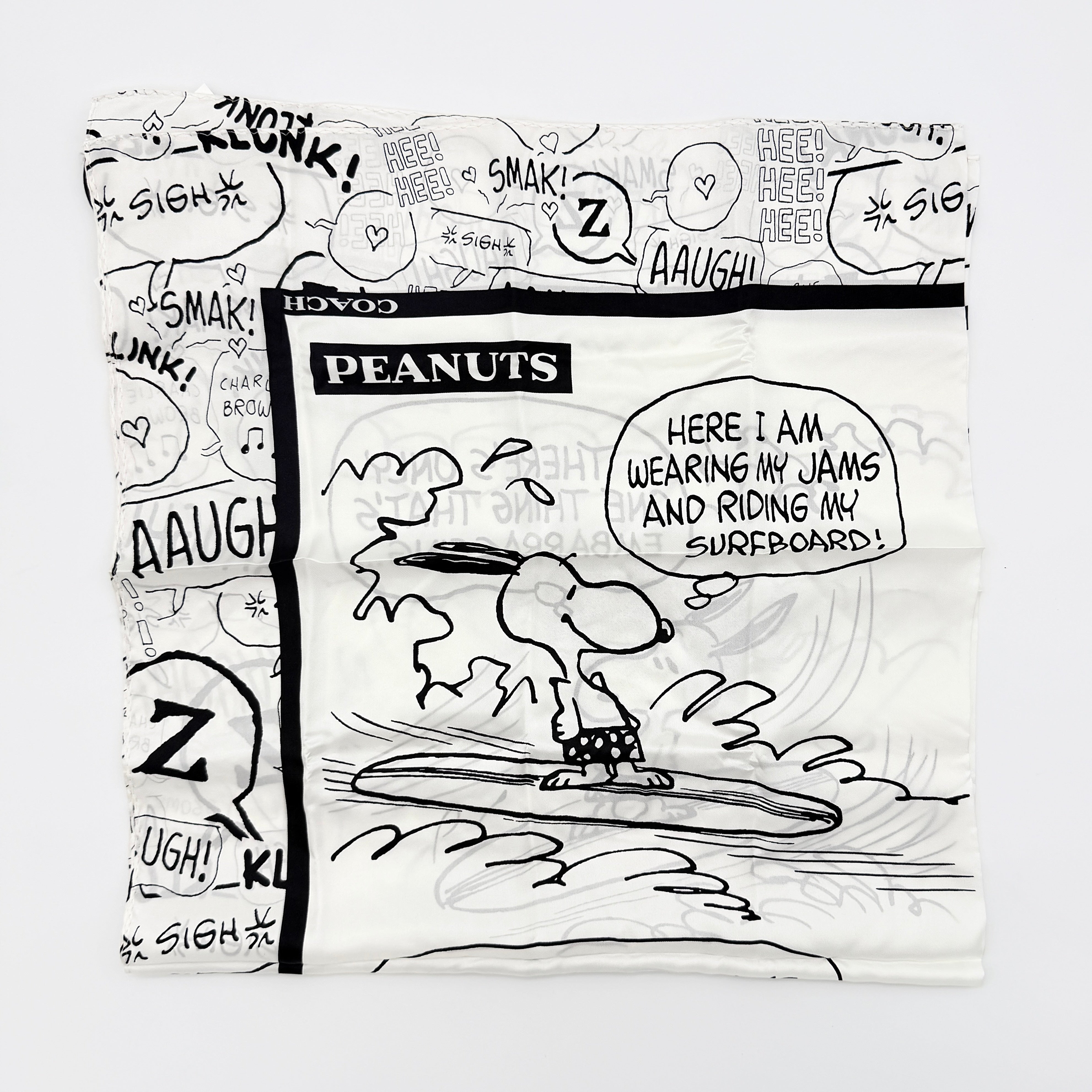 Coach x Peanuts black and white silk scarf featuring a Snoopy surfing comic print, shown with Coach packaging and tags.