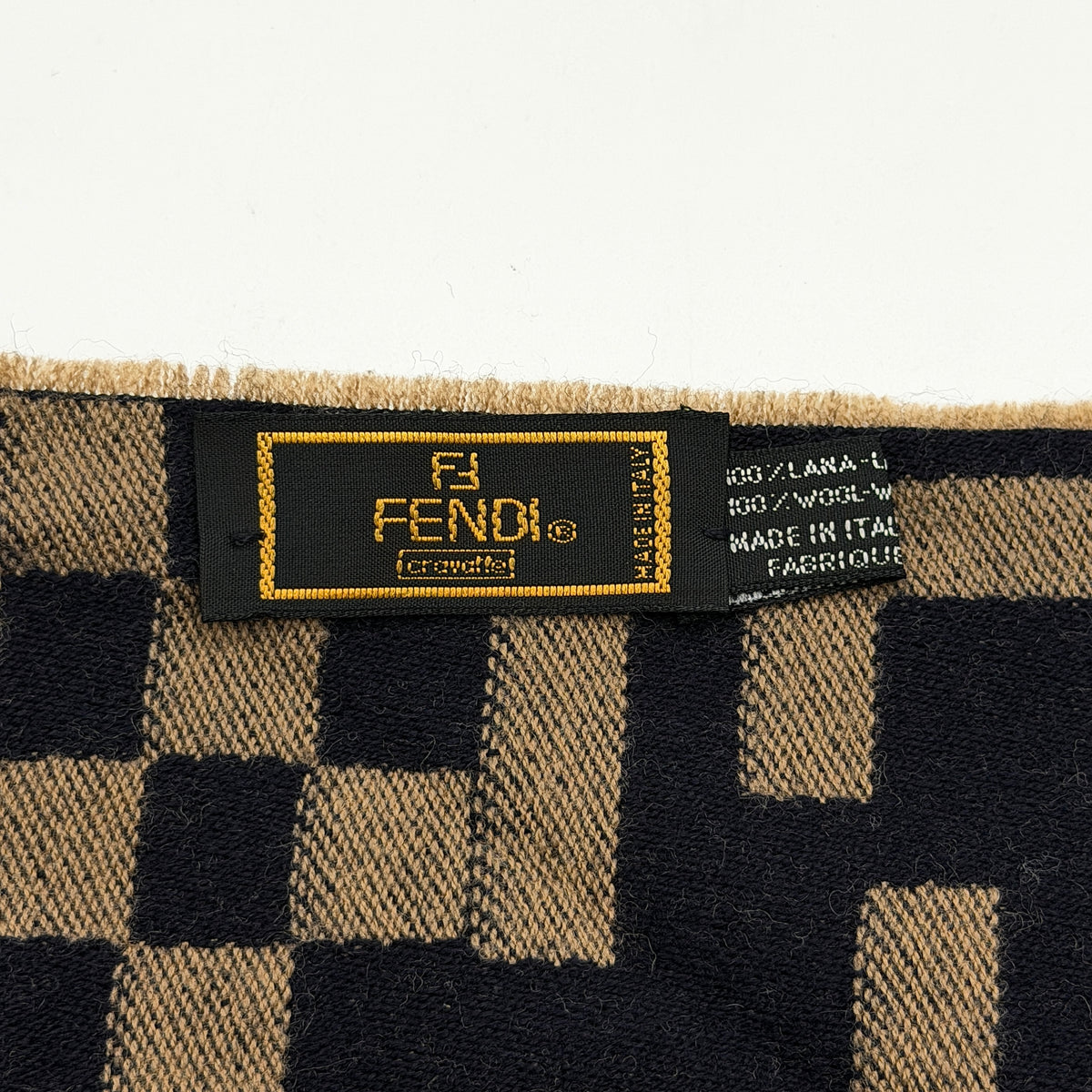 Fendi FF Zucca scarf in beige and black wool with checkered pattern and fringed edges, displayed flat.