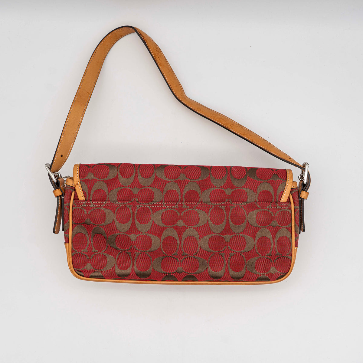 Coach Signature Soho Buckle Baguette in red and tan canvas with leather trim and a silver buckle, shown on a white background.