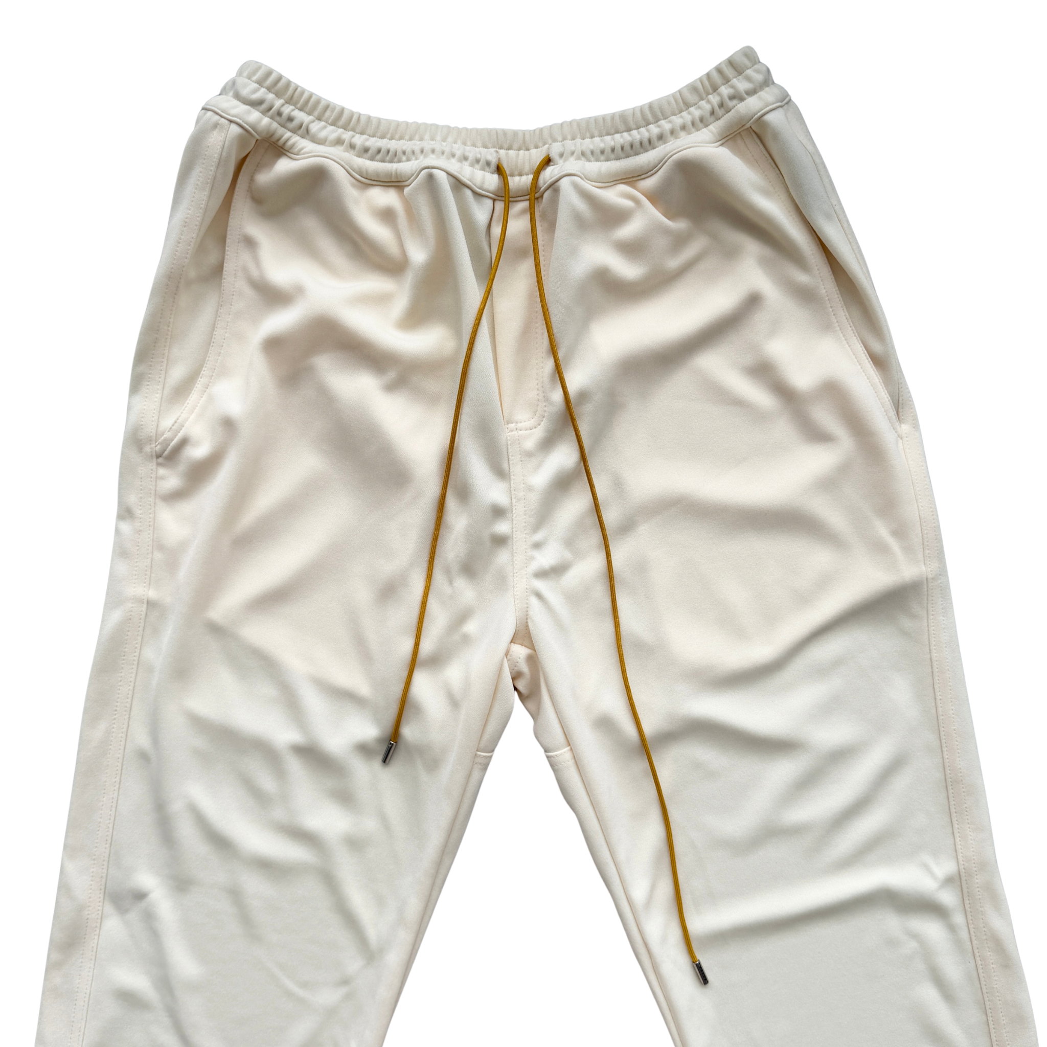 Rhude lounge track pants in cream with yellow drawstrings, displayed flat against a white background.