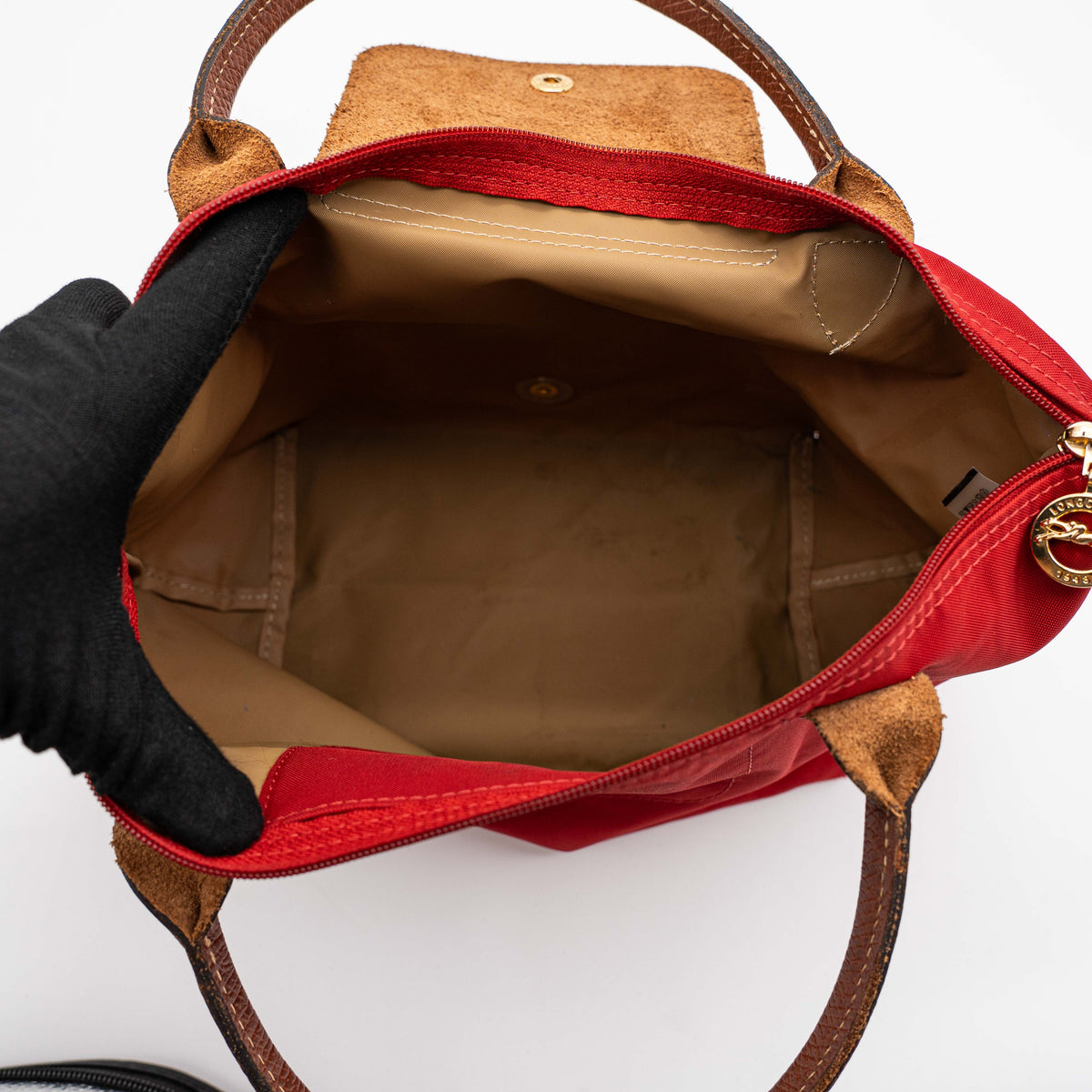 Longchamp Le Pliage handbag in red nylon with brown leather handles and gold-tone accents, photographed on a white background.