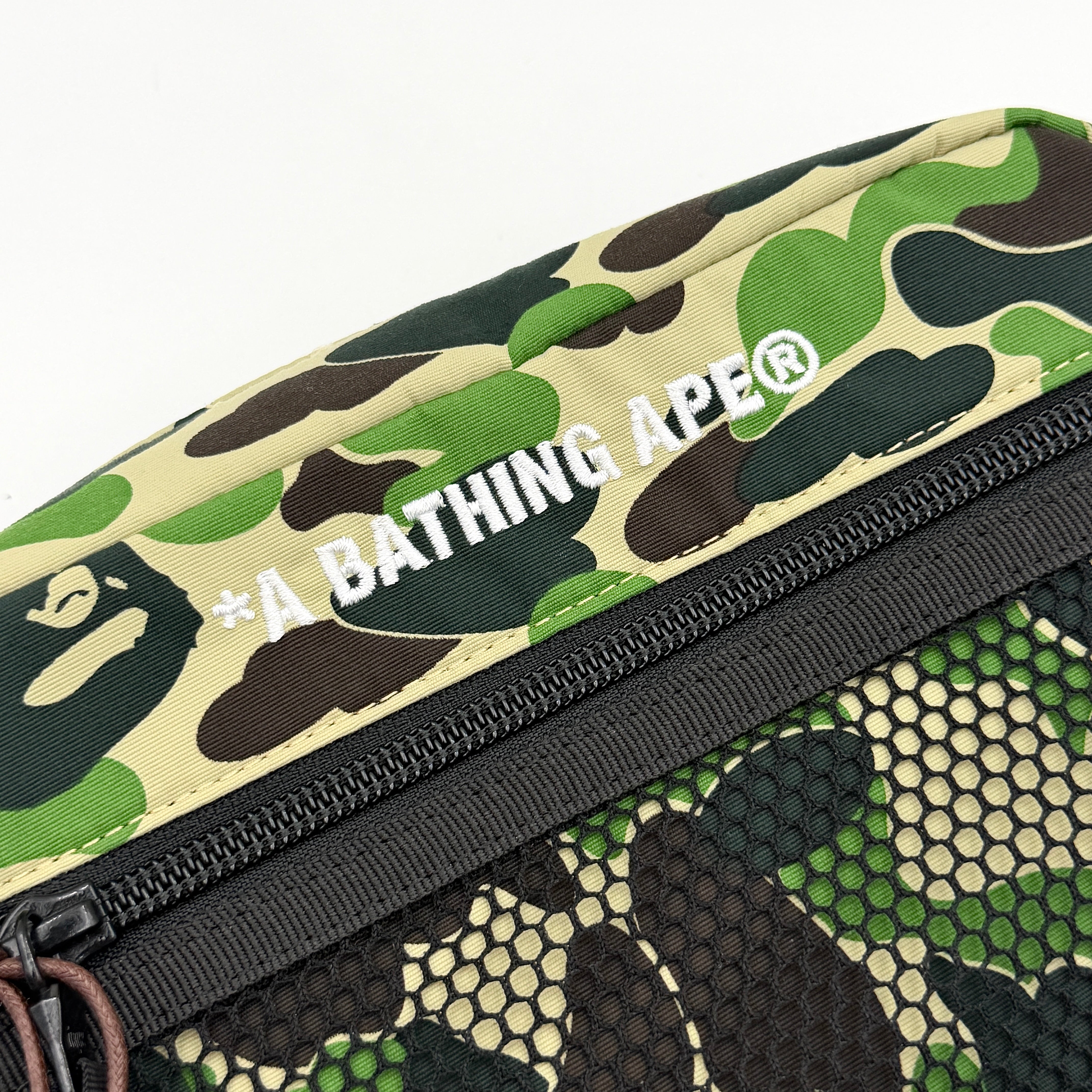 BAPE ABC Camo Pouch in green camouflage with mesh front pocket and embroidered A Bathing Ape logo.
