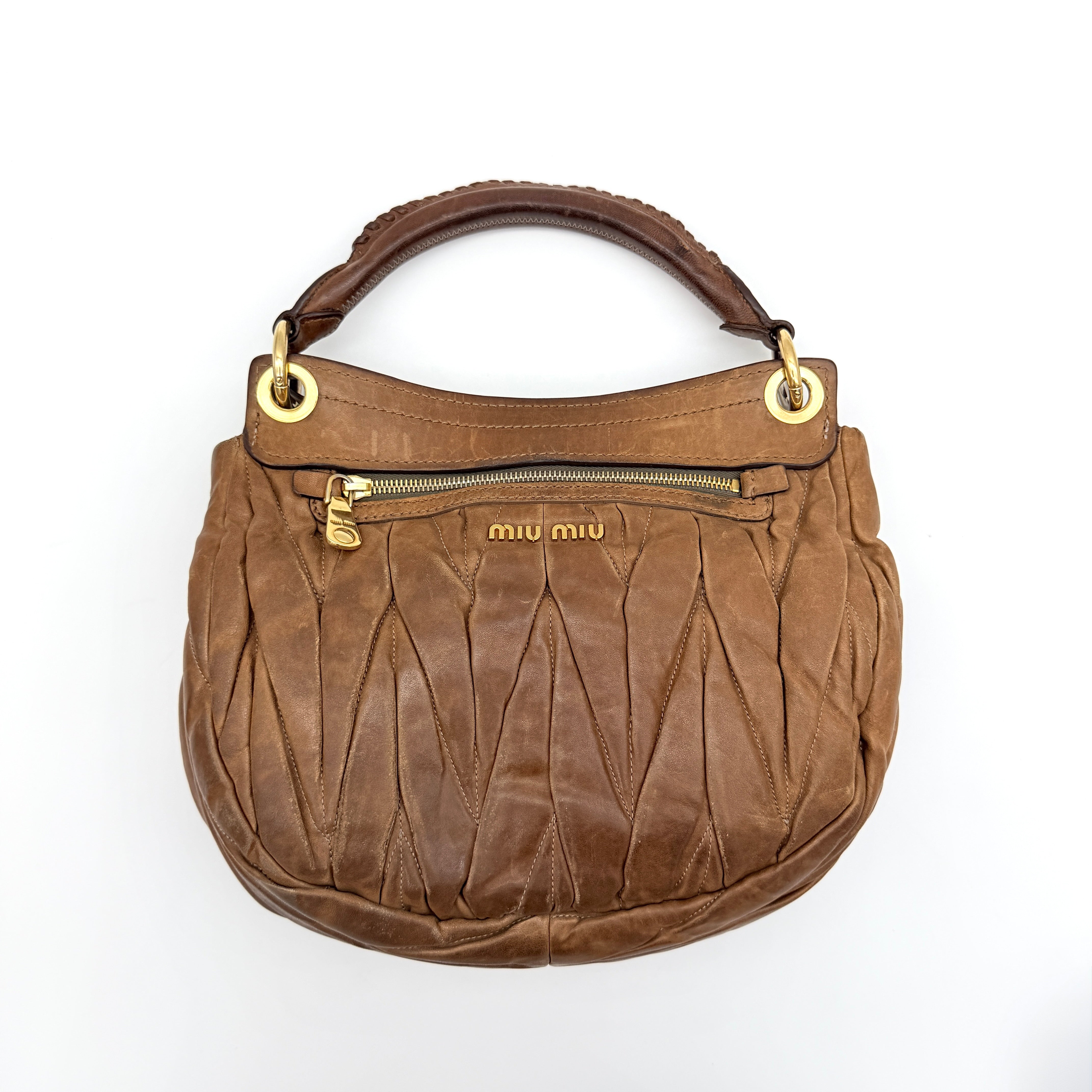 Miu Miu brown Matelasse Coffer Hobo bag with gold hardware, detachable strap, and dust bag displayed on a flat surface.