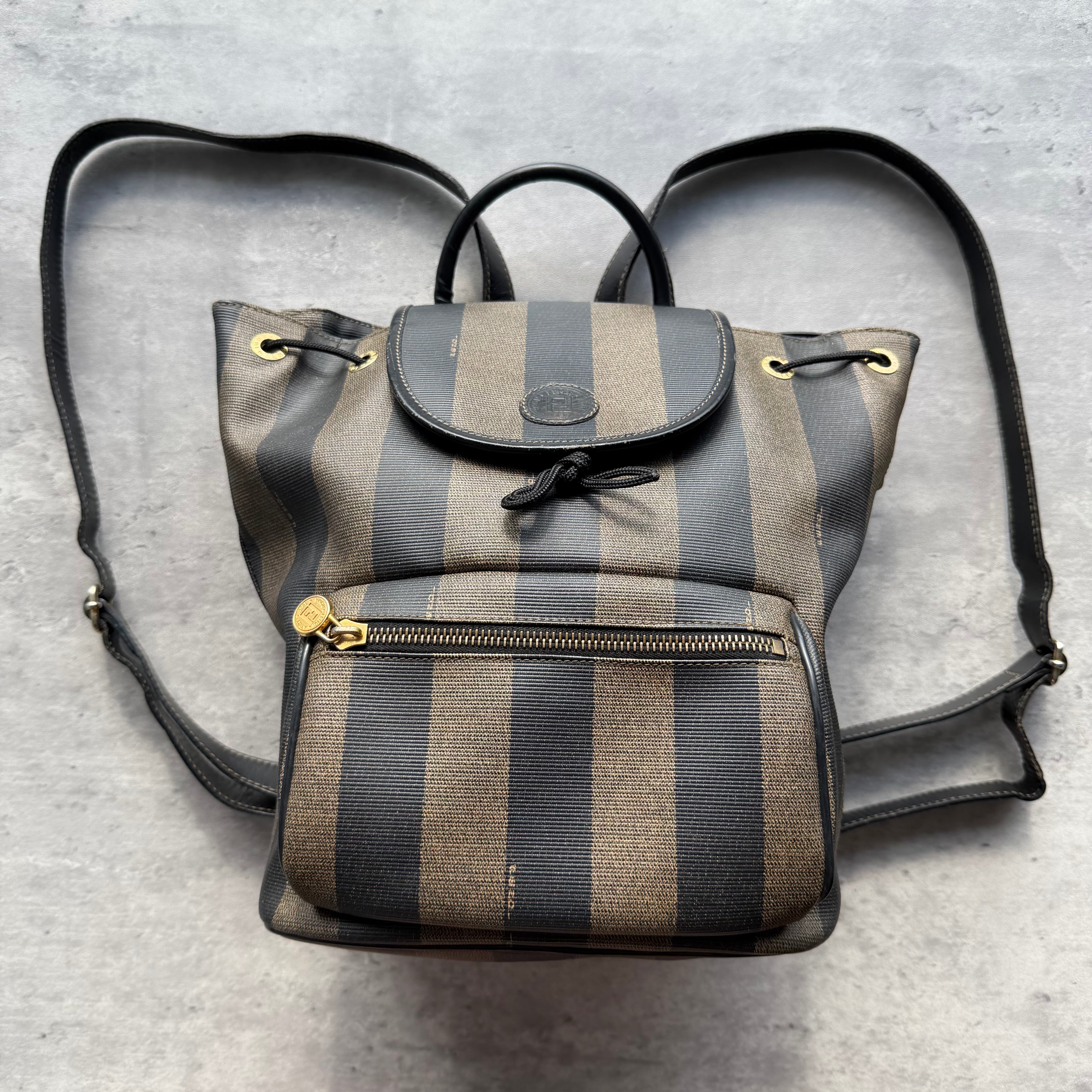 Fendi Pequin Drawstring Backpack in brown and black coated canvas with gold-tone hardware and striped design.