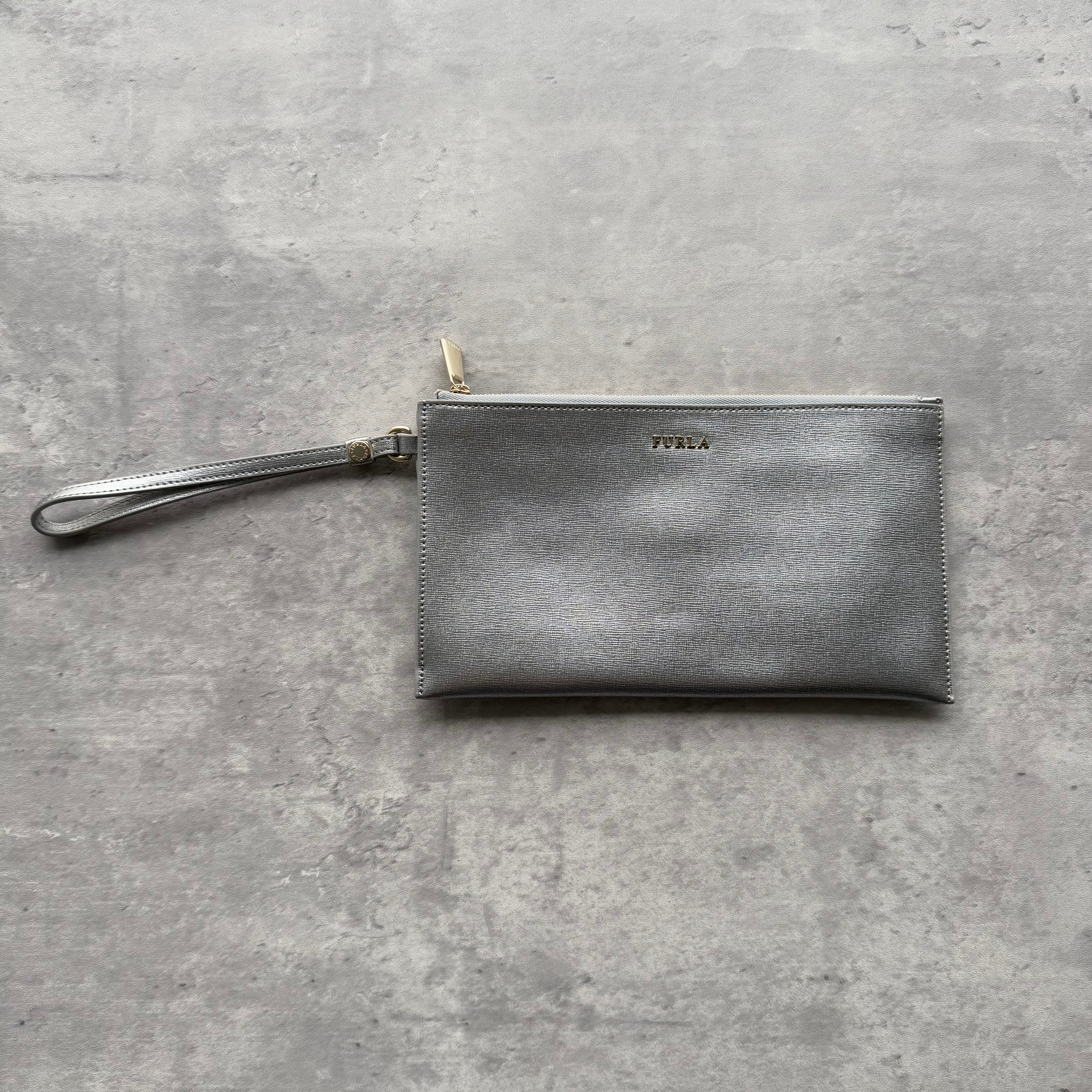 Furla XL Envelope Metallic Silver Wristlet in textured leather with gold-tone hardware, detachable wrist strap, and multiple card slots inside.