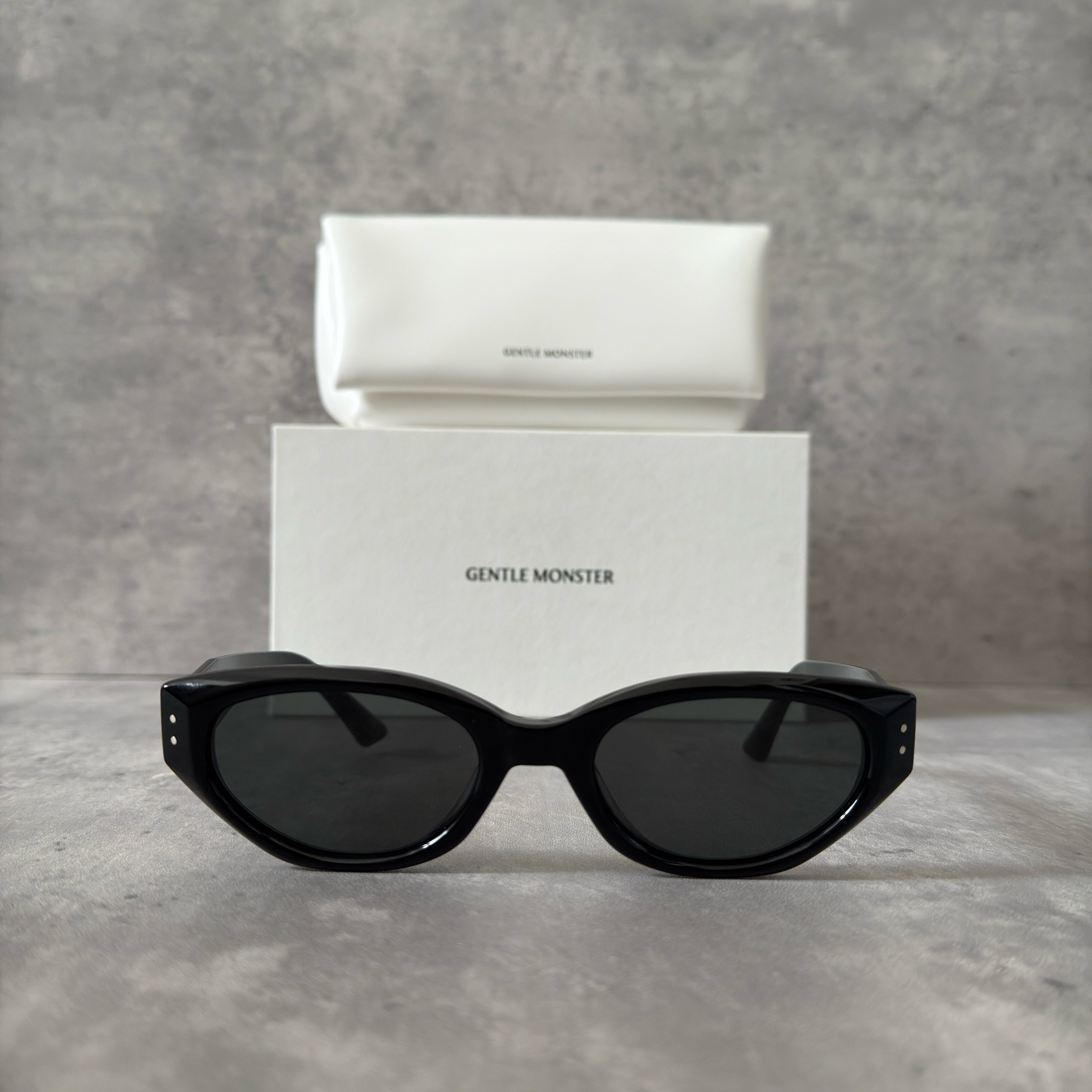 Gentle Monster ROCOCO - 01 black tinted sunglasses with a sleek acetate frame and gold-tone logo on temples.
