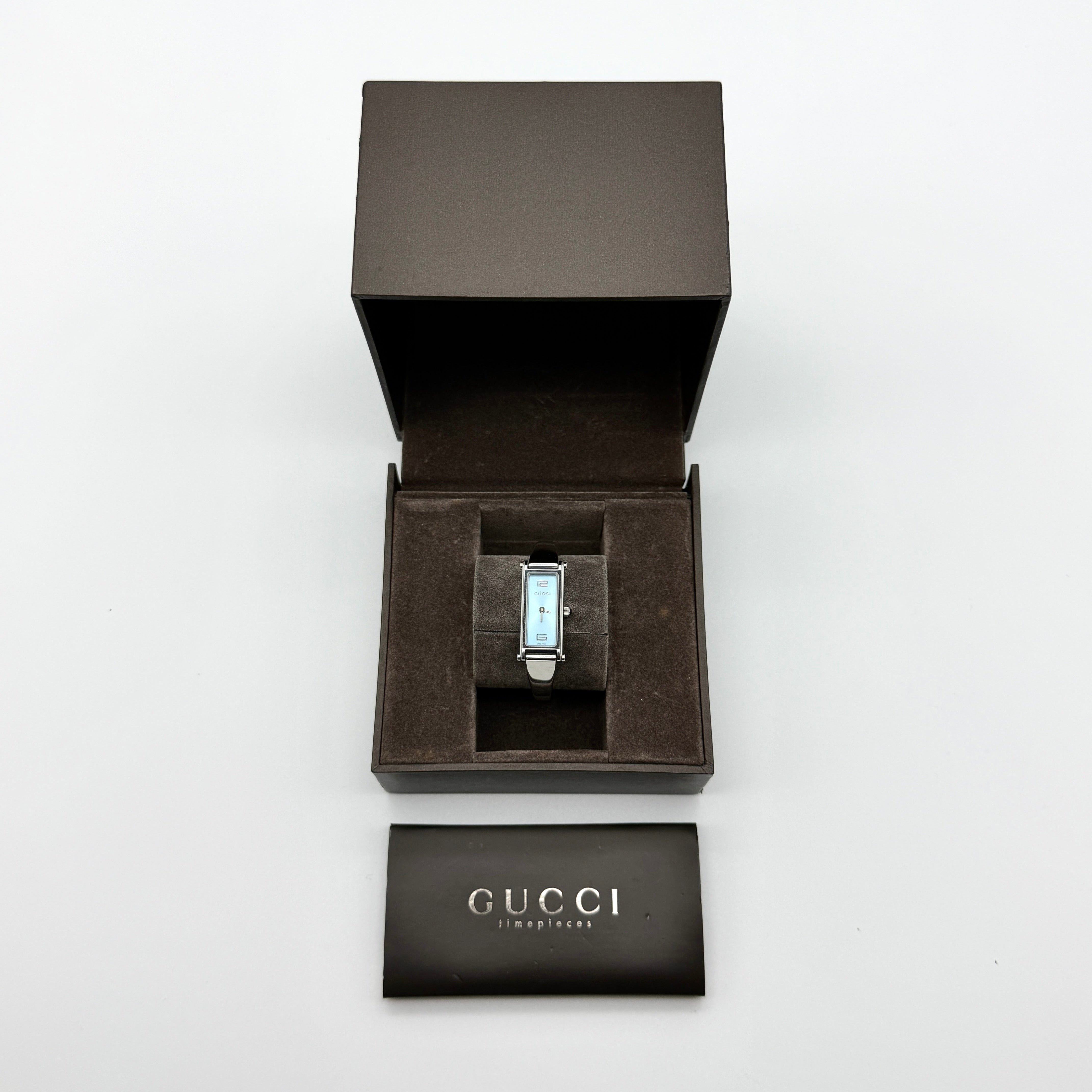 Gucci 1500L stainless steel bangle watch with sky blue rectangular dial, includes box and booklet — pre-loved.