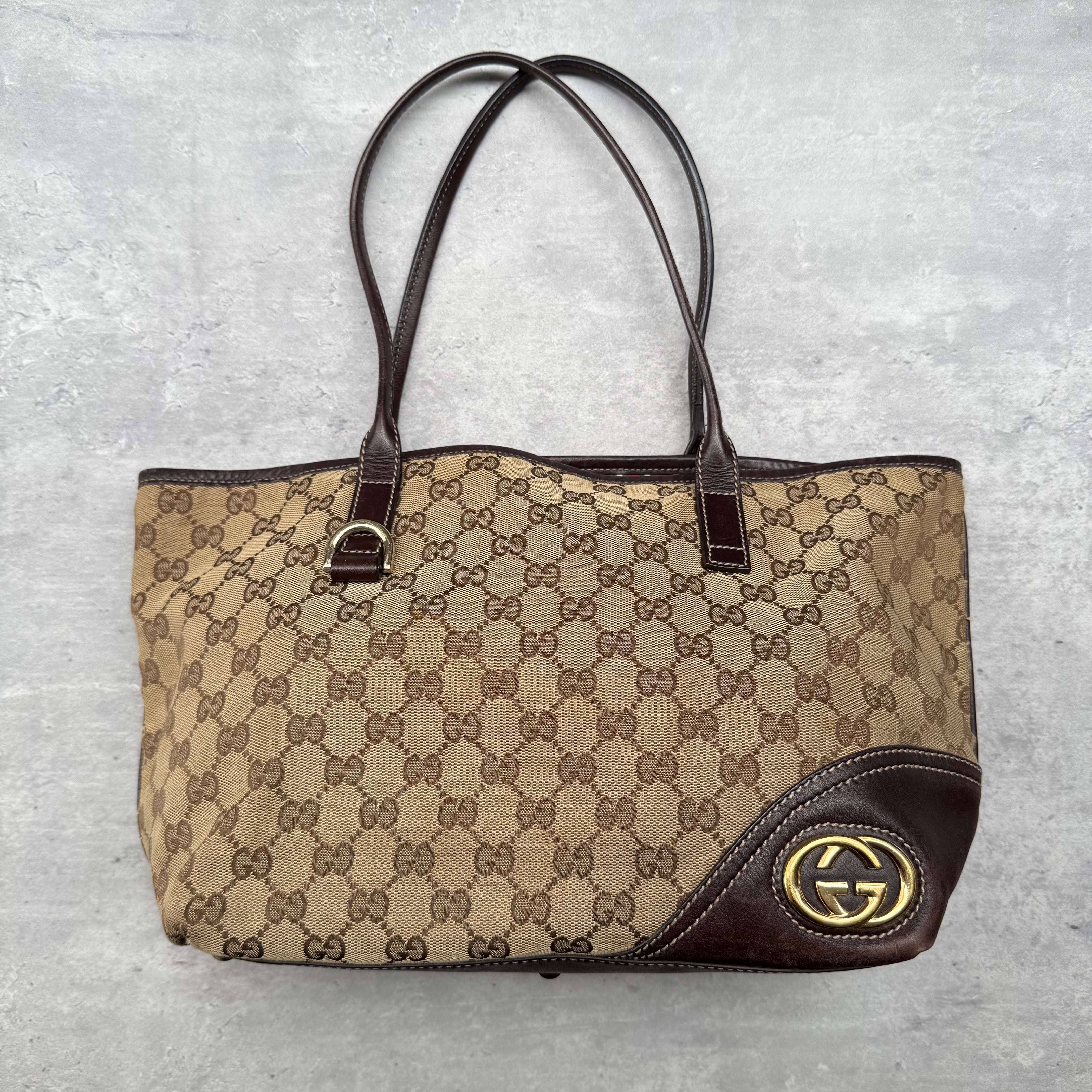 Gucci Britt GG Monogram Tote Bag in beige canvas with brown leather trim and gold-tone interlocking GG emblem.