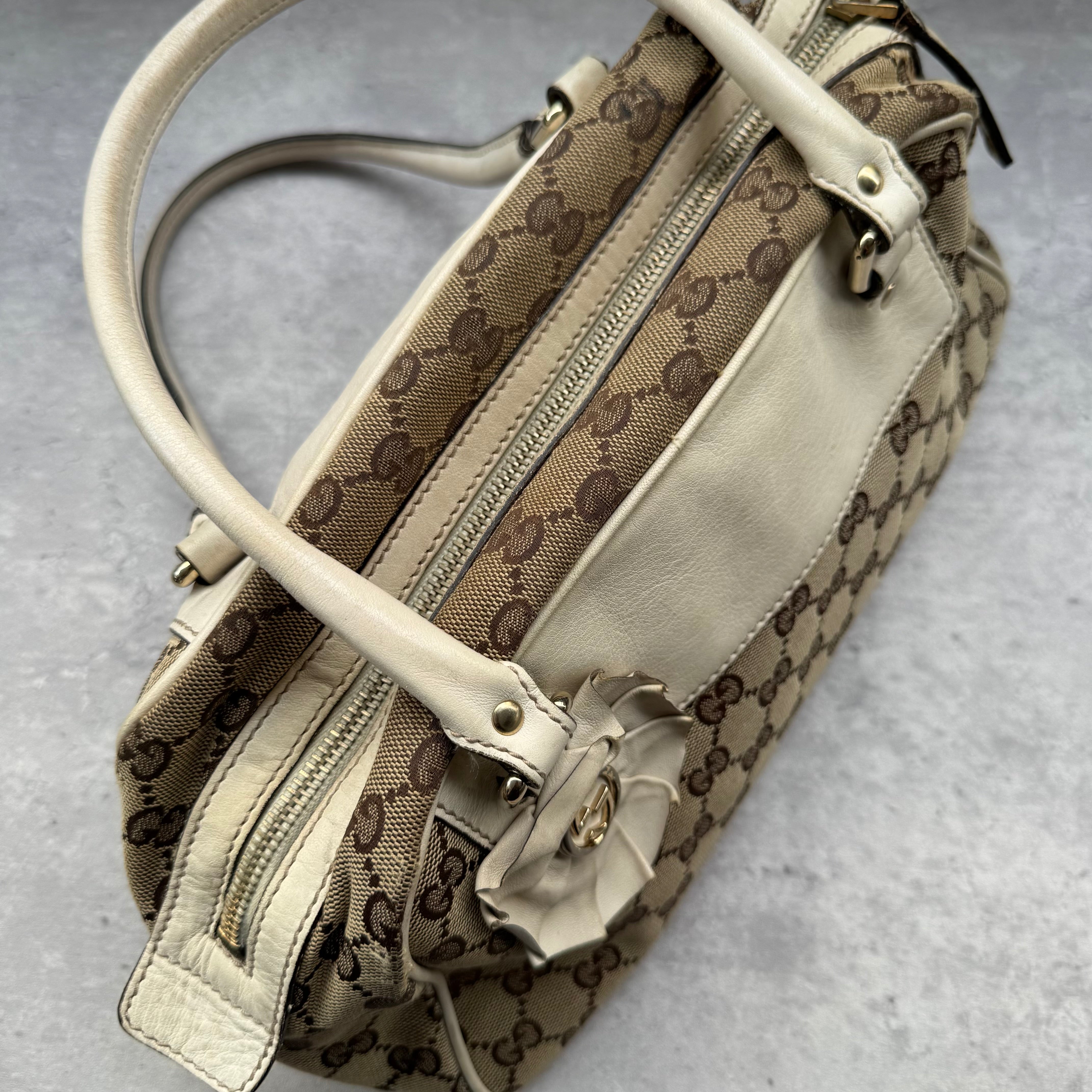 Gucci GG Canvas Trophy Boston Bag in beige monogram canvas with cream leather trim and floral GG emblem detail.
