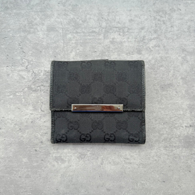 Gucci GG Monogram Compact Wallet Black, crafted from monogram canvas with leather trim, featuring silver-tone bar detail and organized interior.