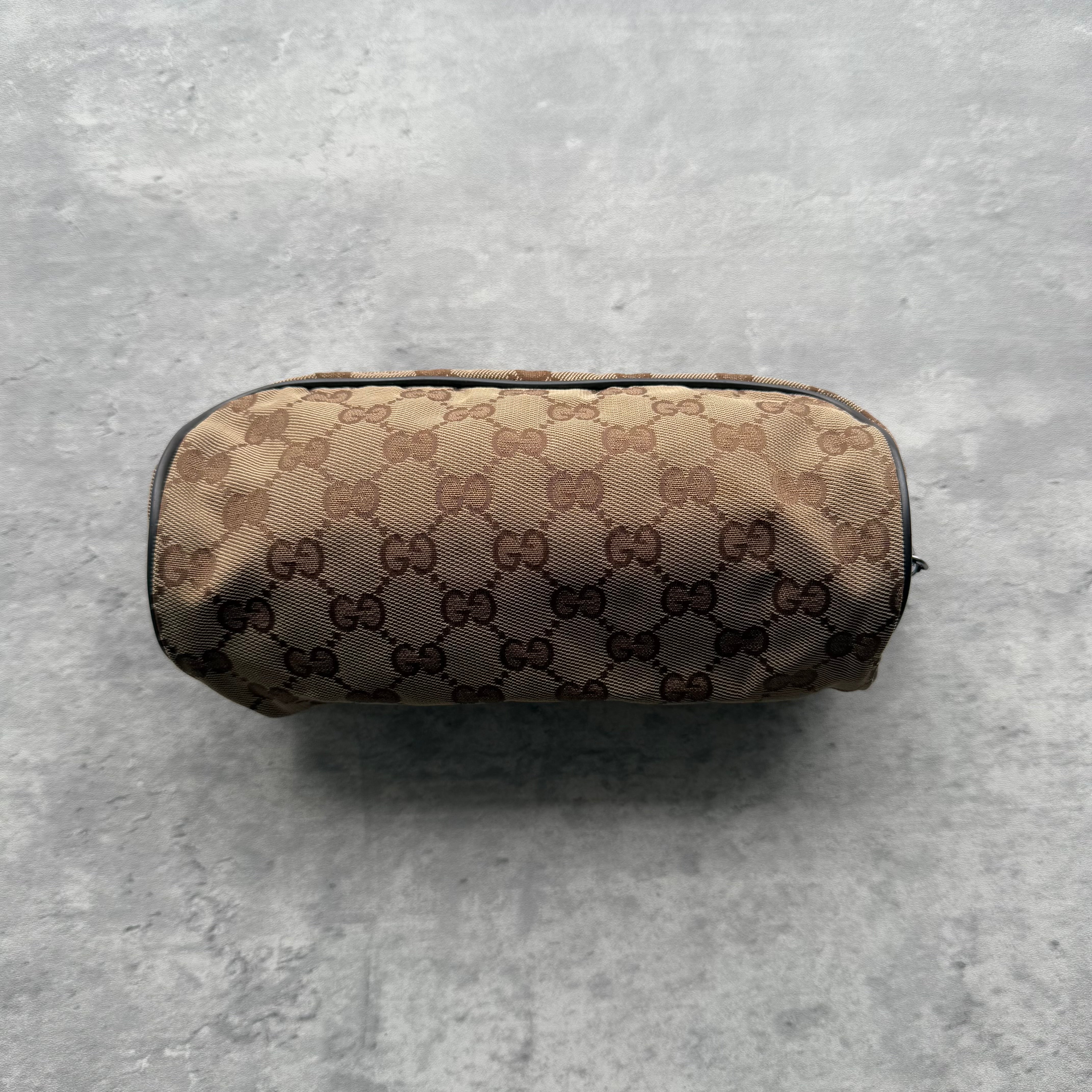 Gucci GG Monogram Cosmetic Pouch in beige canvas with brown leather trim and top zip closure.