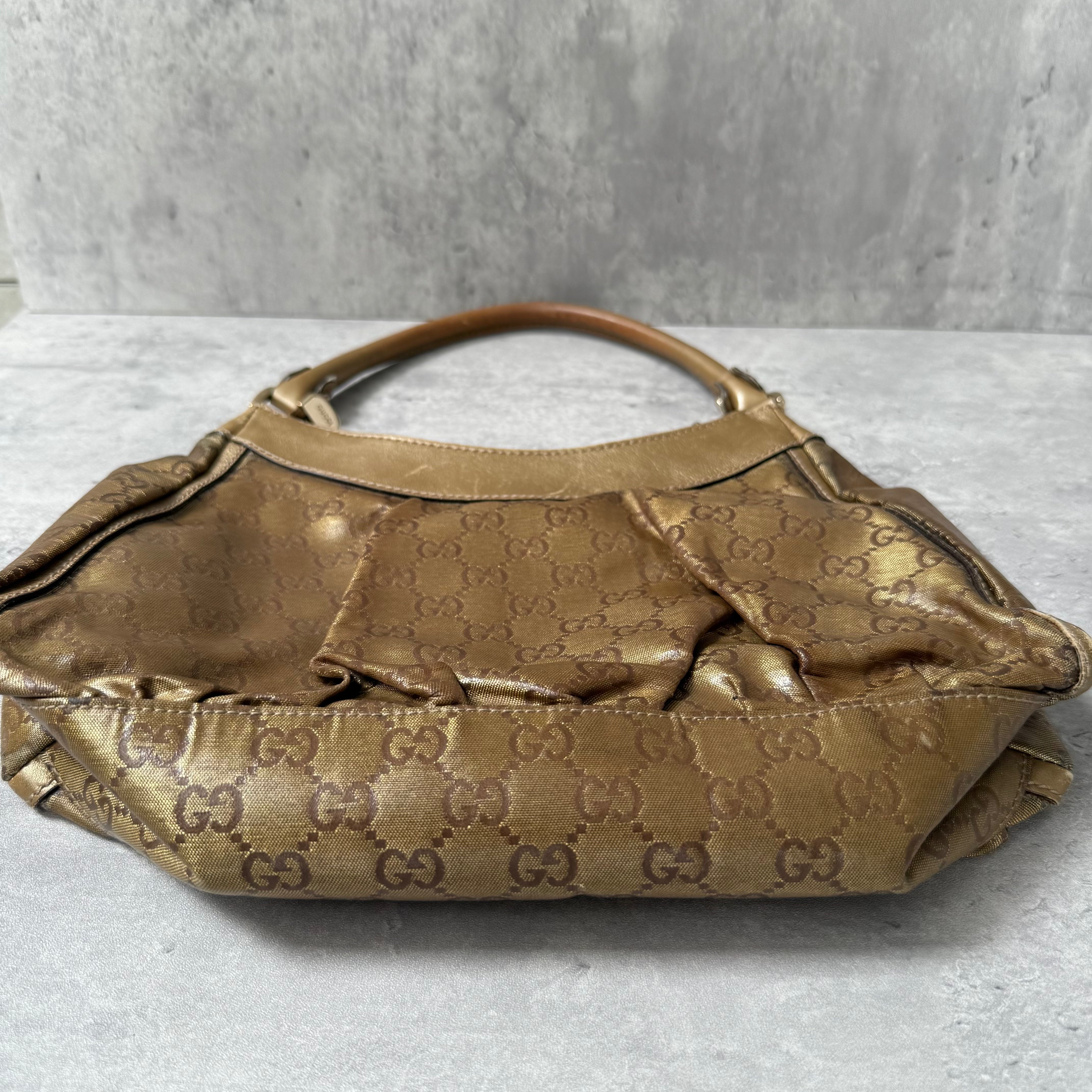 Gucci GG Monogram D-Ring Shoulder Bag in metallic gold with patent leather trim, pleated body, and gold-tone hardware.