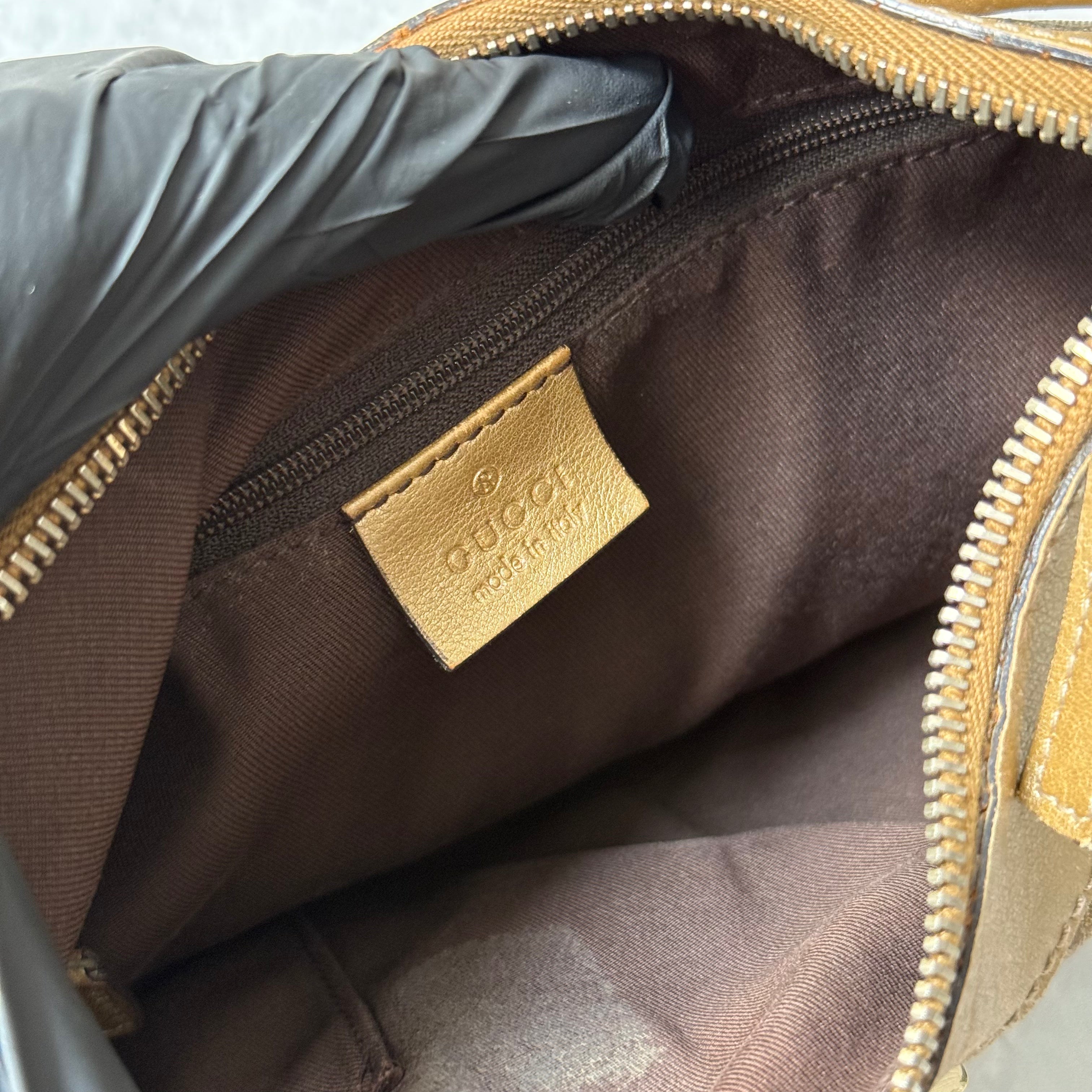 Gucci GG Monogram D-Ring Shoulder Bag in metallic gold with patent leather trim, pleated body, and gold-tone hardware.