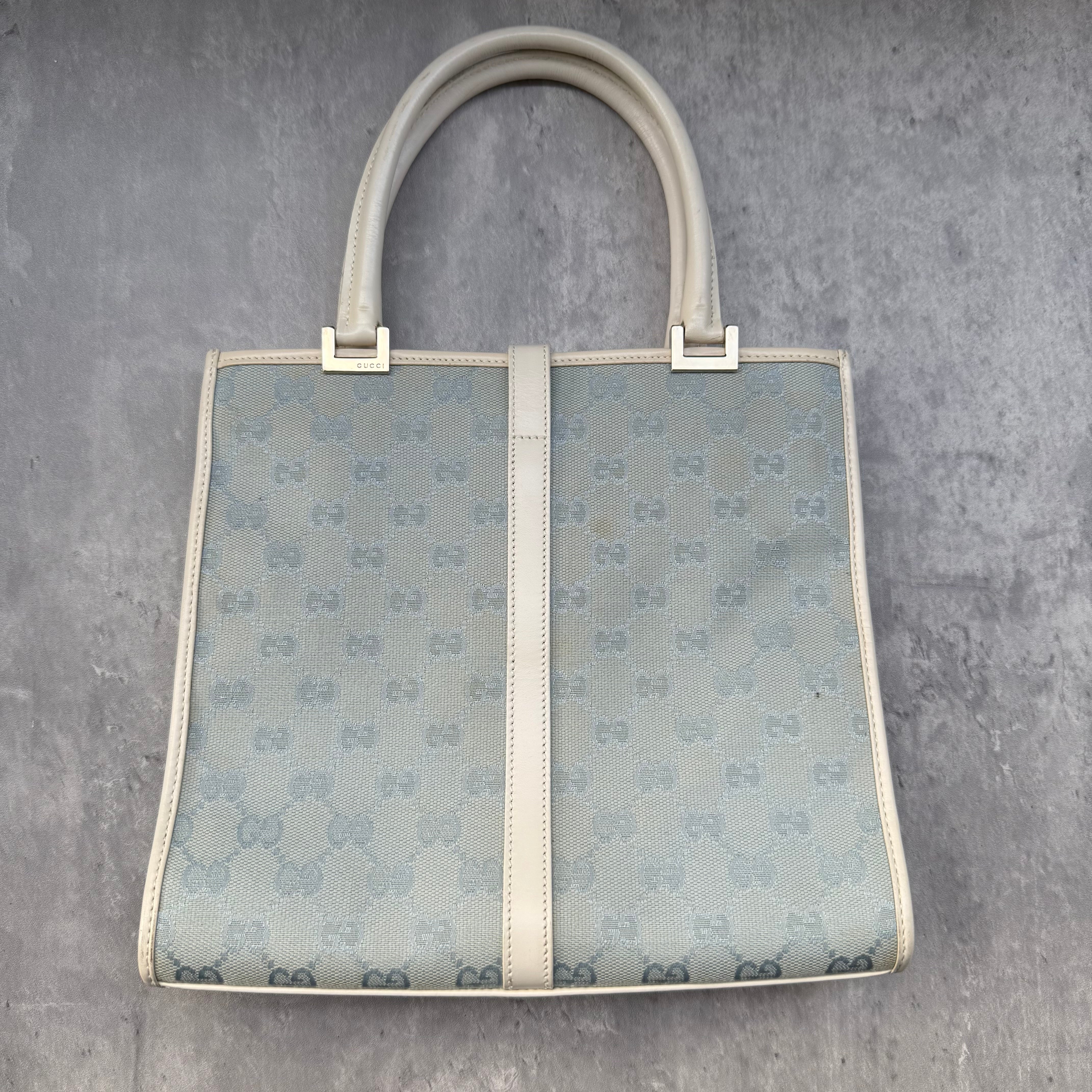Gucci GG Monogram Jackie Shoulder Bag in light blue canvas with white leather trim, structured silhouette, and silver-tone piston lock.