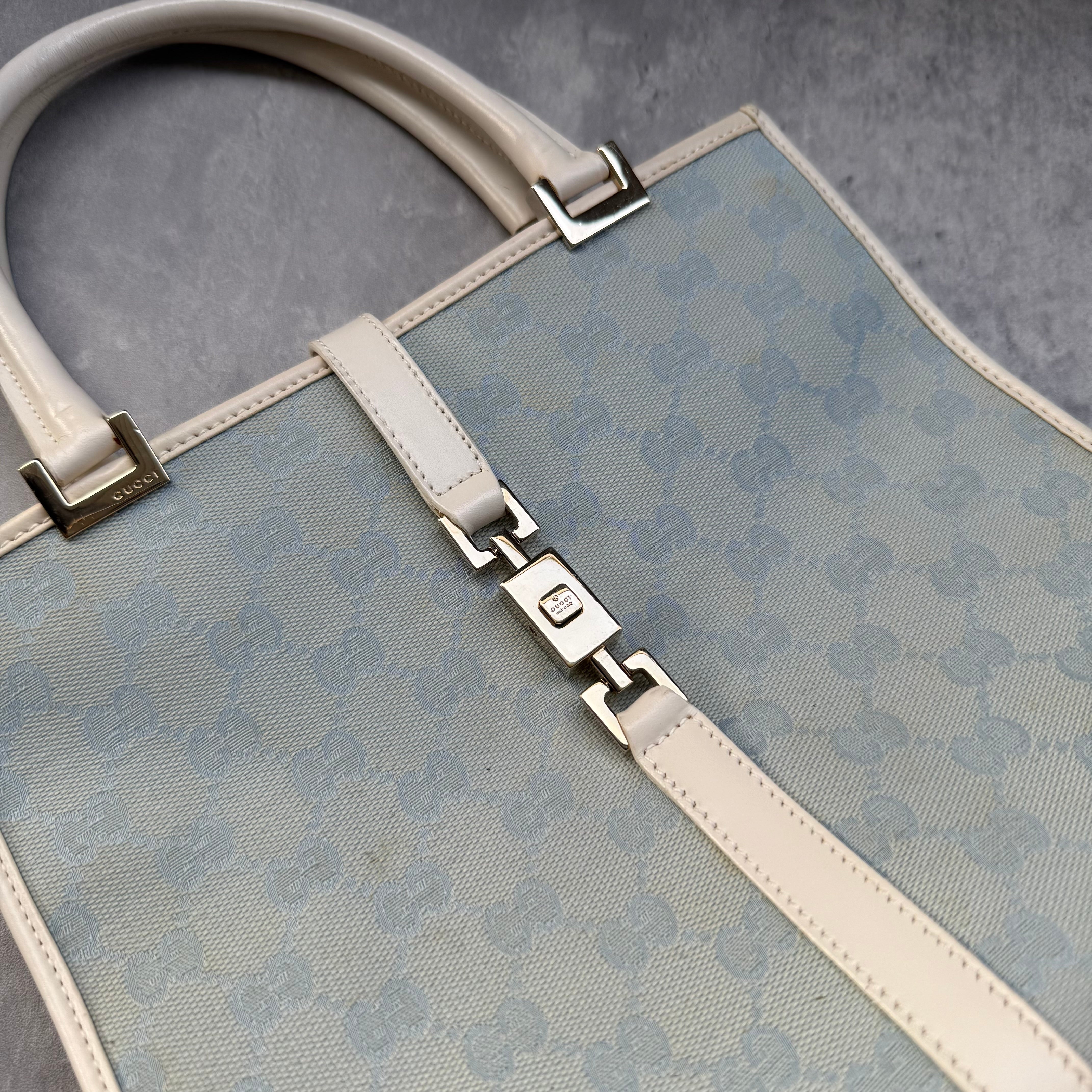 Gucci GG Monogram Jackie Shoulder Bag in light blue canvas with white leather trim, structured silhouette, and silver-tone piston lock.