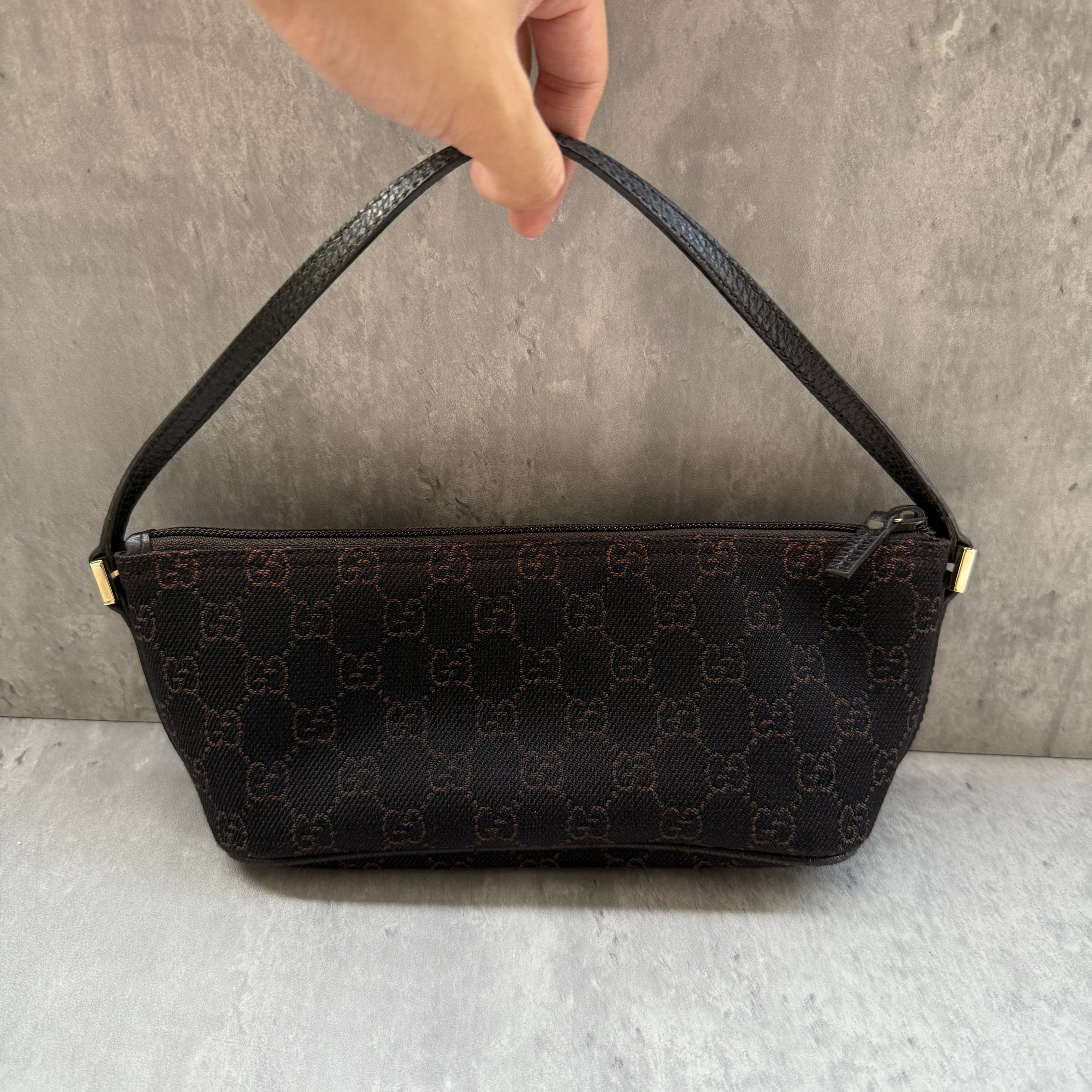 Gucci GG Monogram Pochette Boat Shoulder Bag in black canvas with tonal trim, top zip closure, and minimalist silhouette.