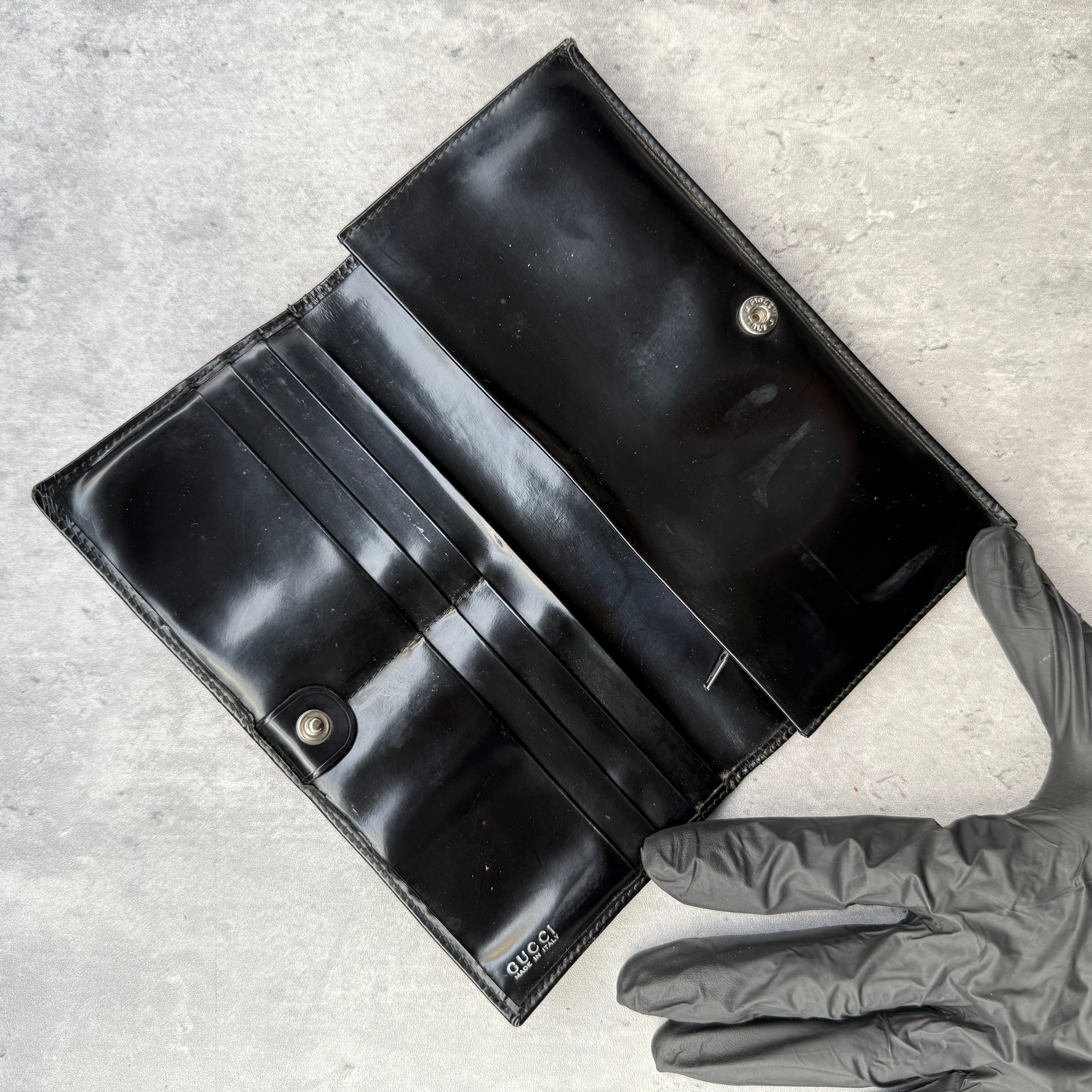 Gucci black patent leather bifold wallet with interlocking GG logo, original Gucci care card, and structured compartments