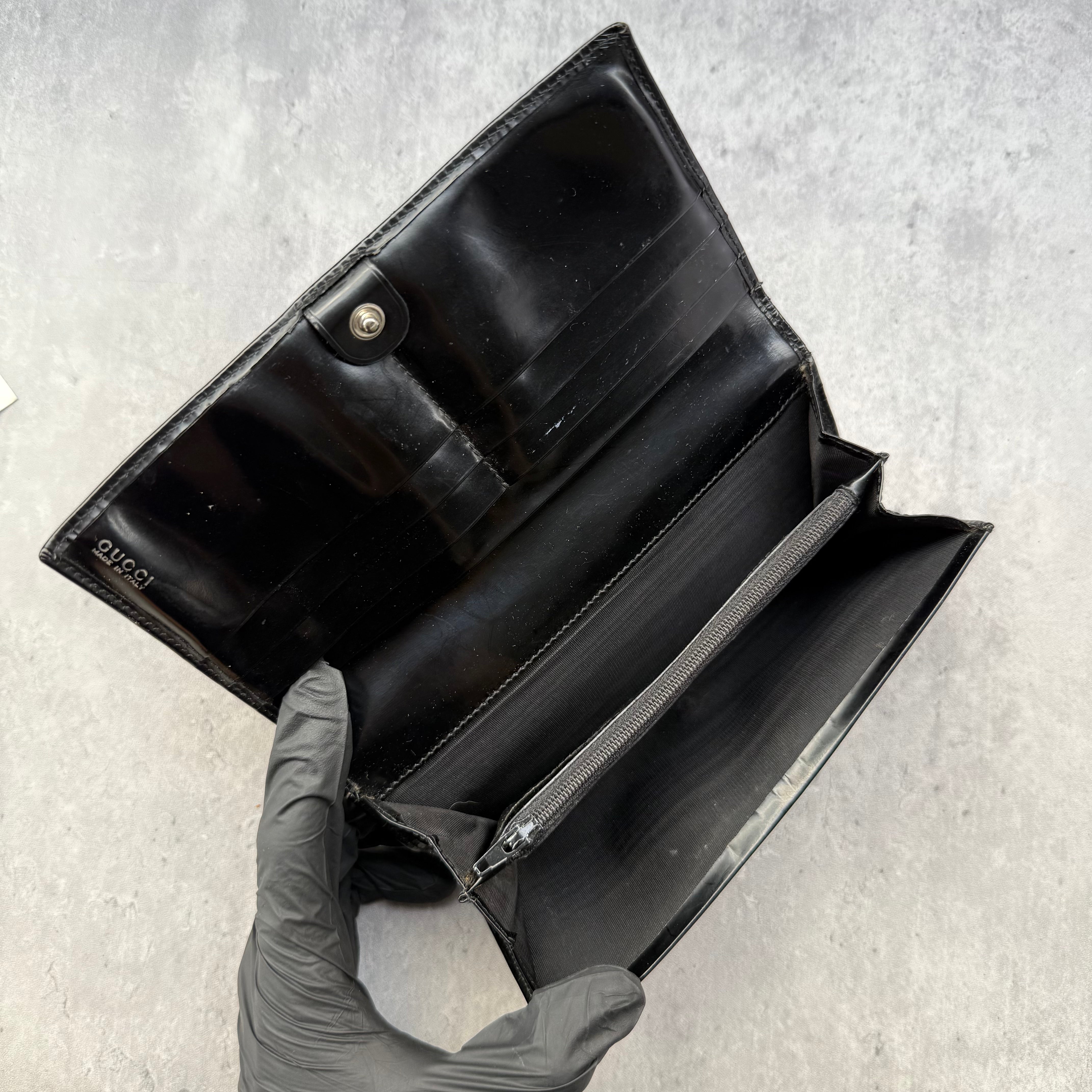 Gucci black patent leather bifold wallet with interlocking GG logo, original Gucci care card, and structured compartments