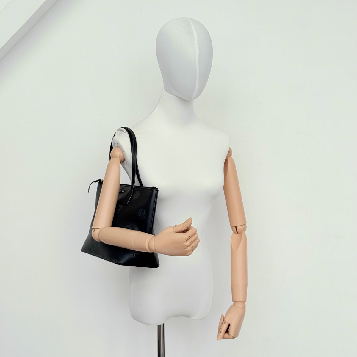 Front view of a Kate Spade black tote bag with glitter polka dots and dual handles.
