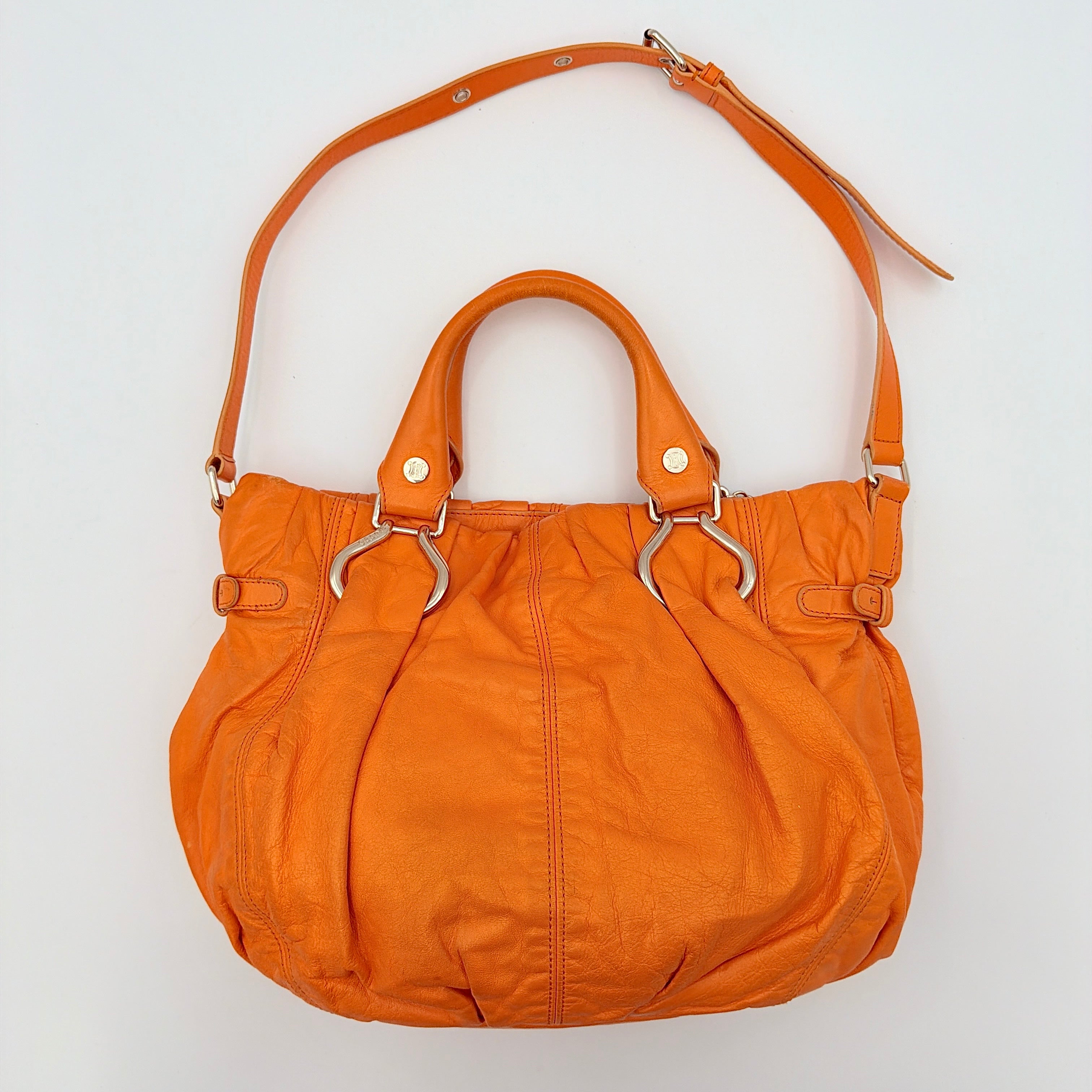 Celine 2Way Shoulder Bag in vibrant orange leather with silver-tone hardware and pleated detailing, shown with both top handles and an adjustable strap.