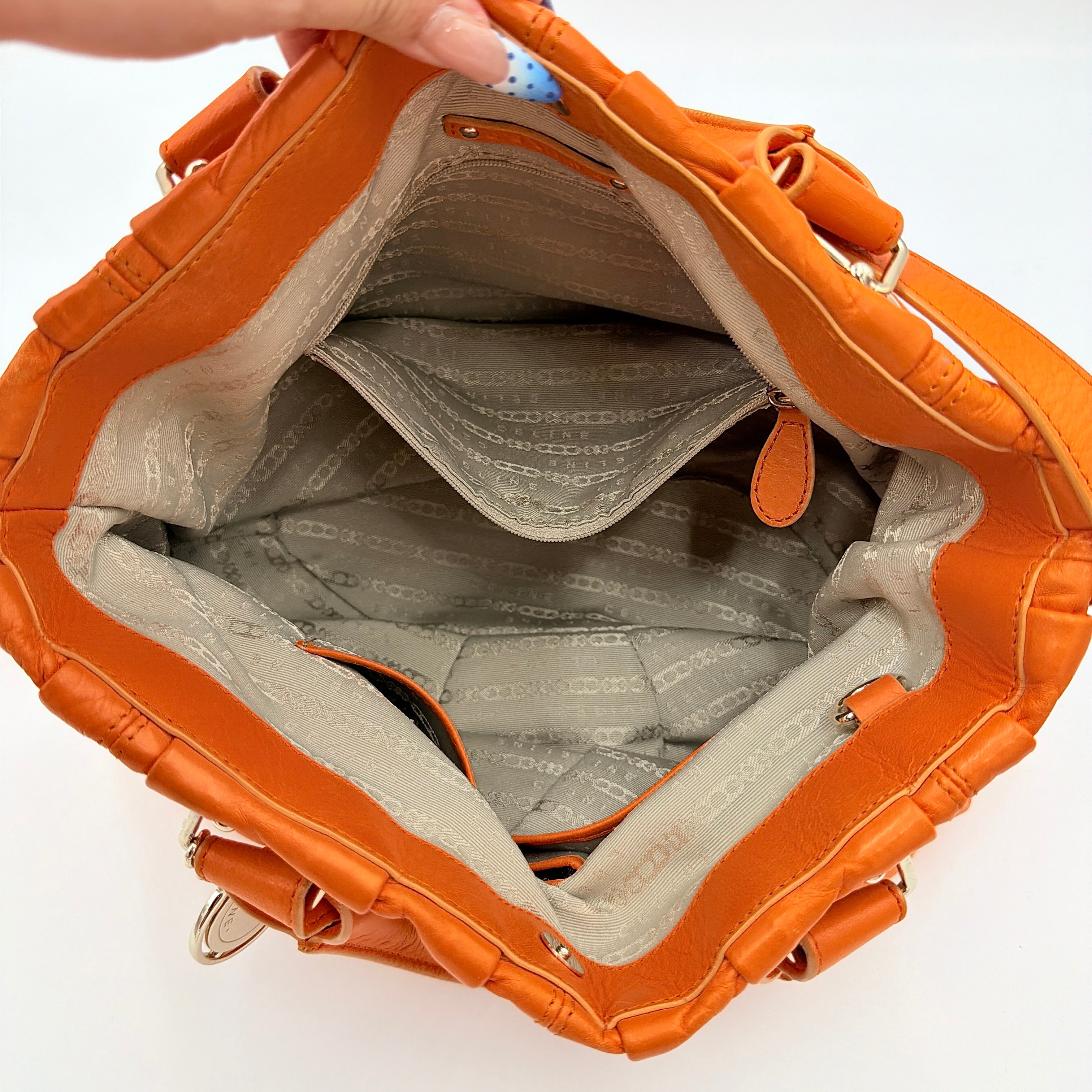 Celine 2Way Shoulder Bag in vibrant orange leather with silver-tone hardware and pleated detailing, shown with both top handles and an adjustable strap.