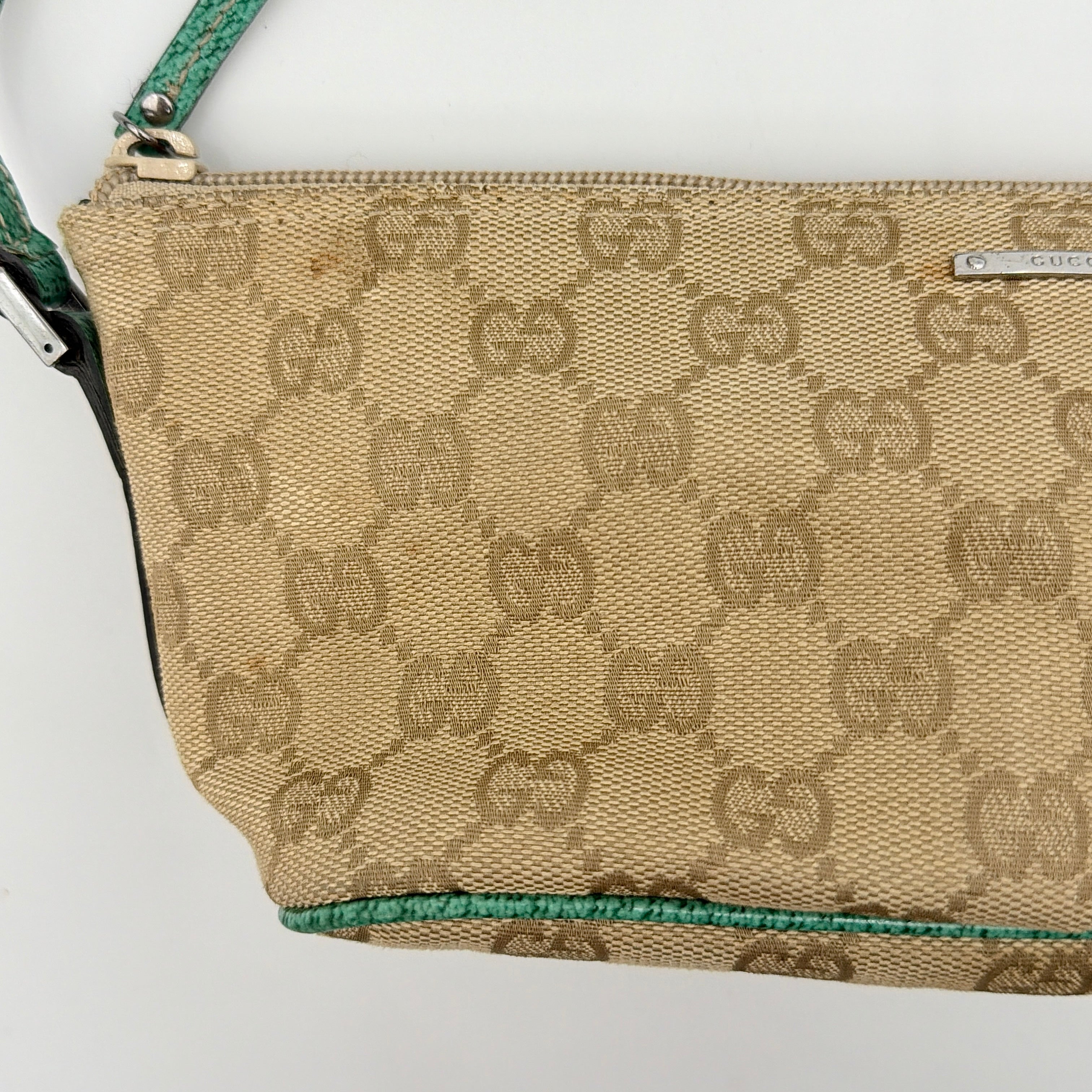 Gucci GG Monogram Pochette Boat Shoulder Bag in beige canvas with green leather trim and a structured, boat-shaped silhouette.