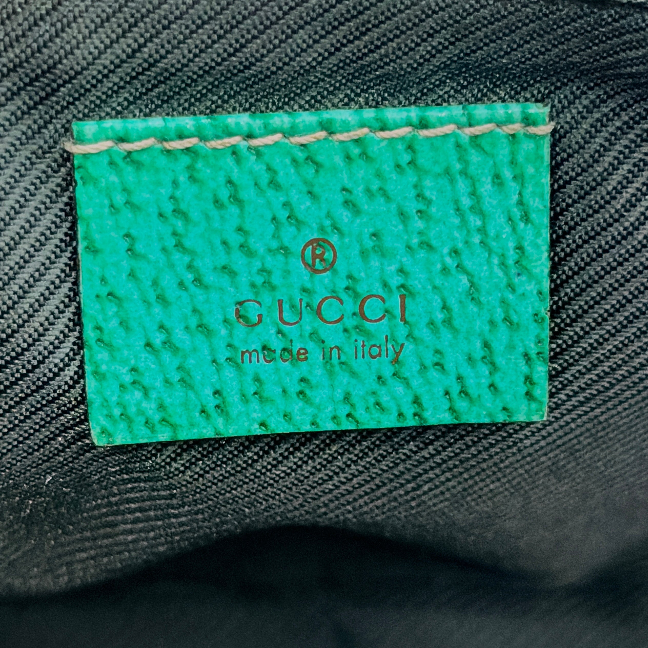 Gucci GG Monogram Pochette Boat Shoulder Bag in beige canvas with green leather trim and a structured, boat-shaped silhouette.