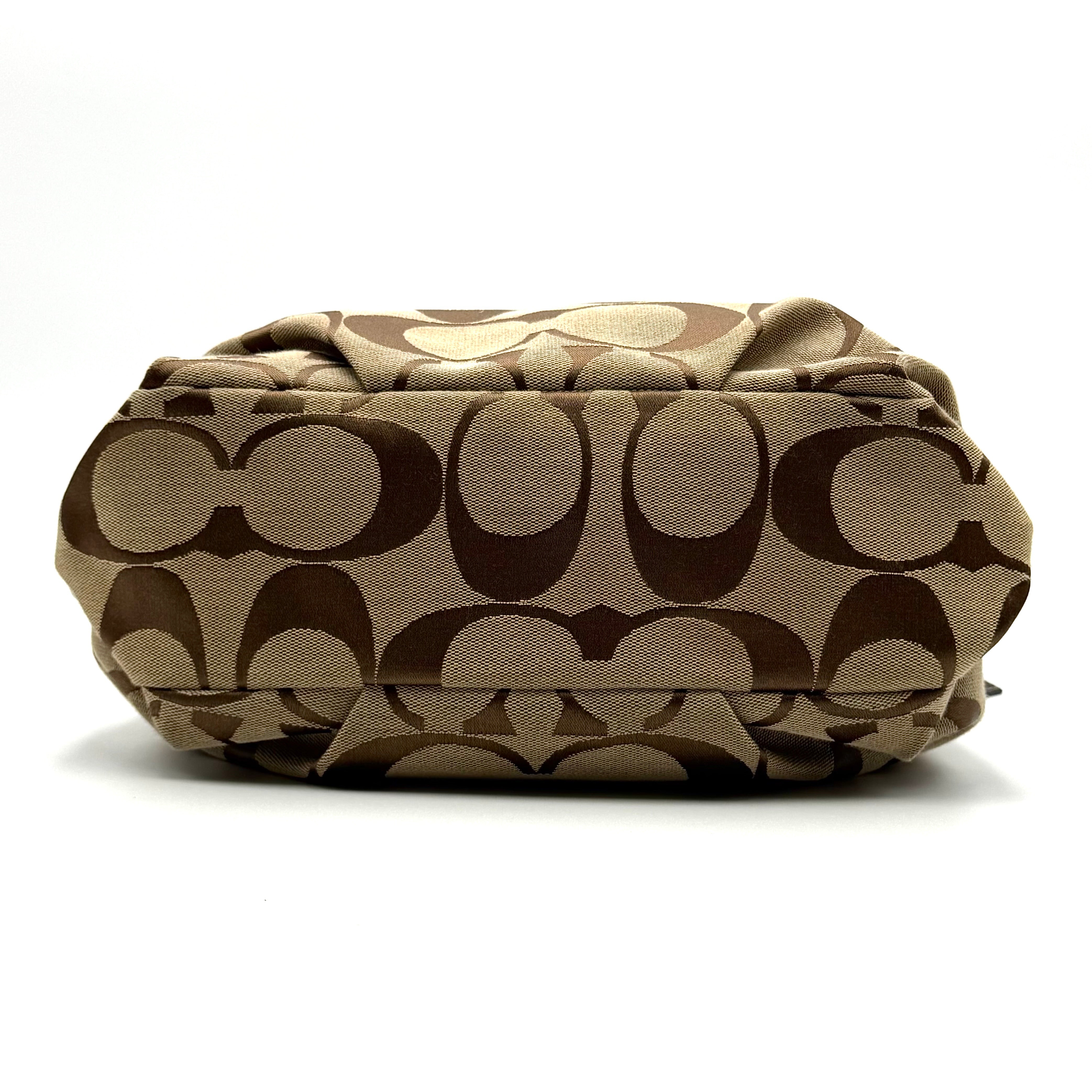 Coach beige and brown signature canvas hobo shoulder bag with black leather strap and silver hardware shown on a white background.