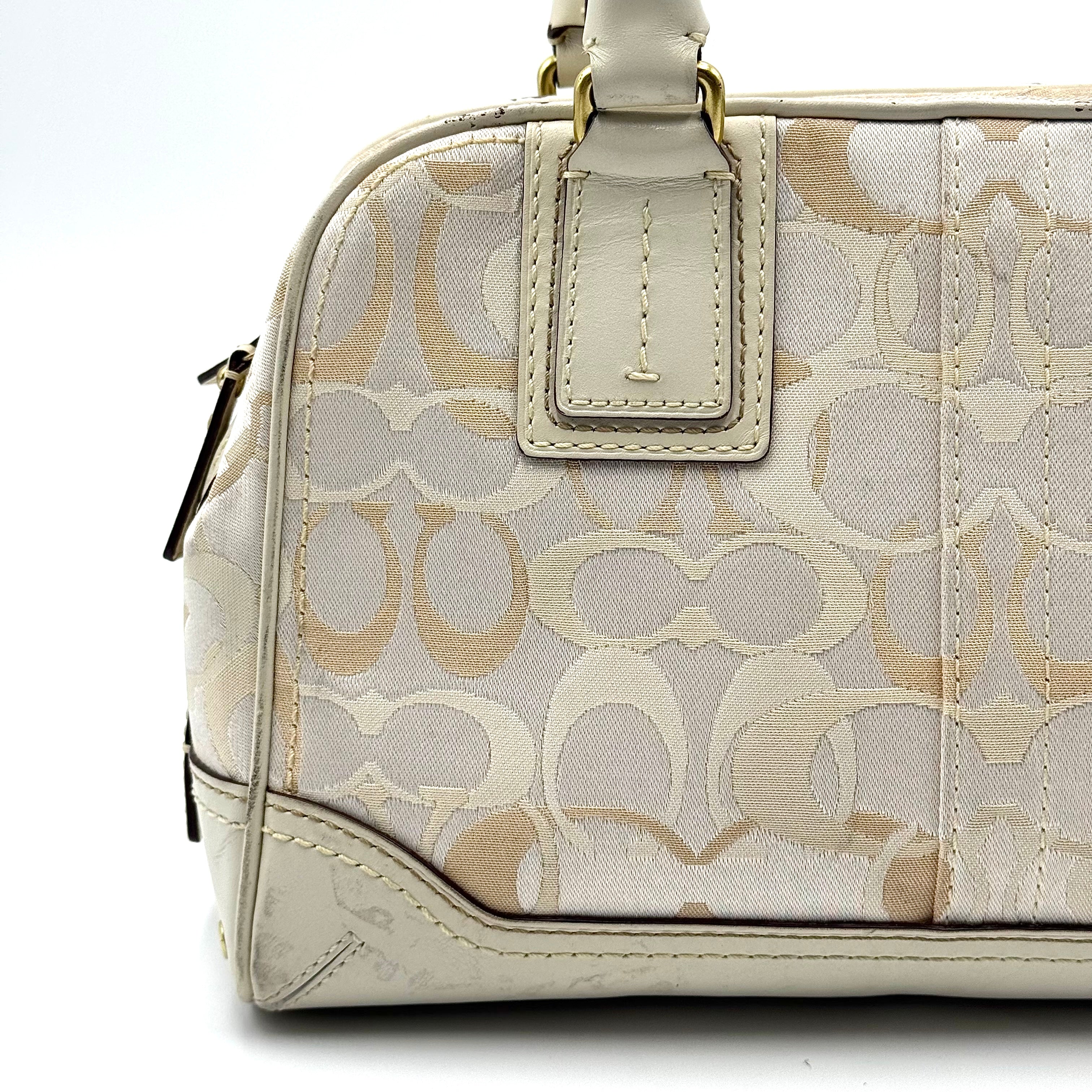 Coach Signature Canvas Satchel in ivory with dual rolled handles, monogram pattern and leather trim shown from the front against a clean background.