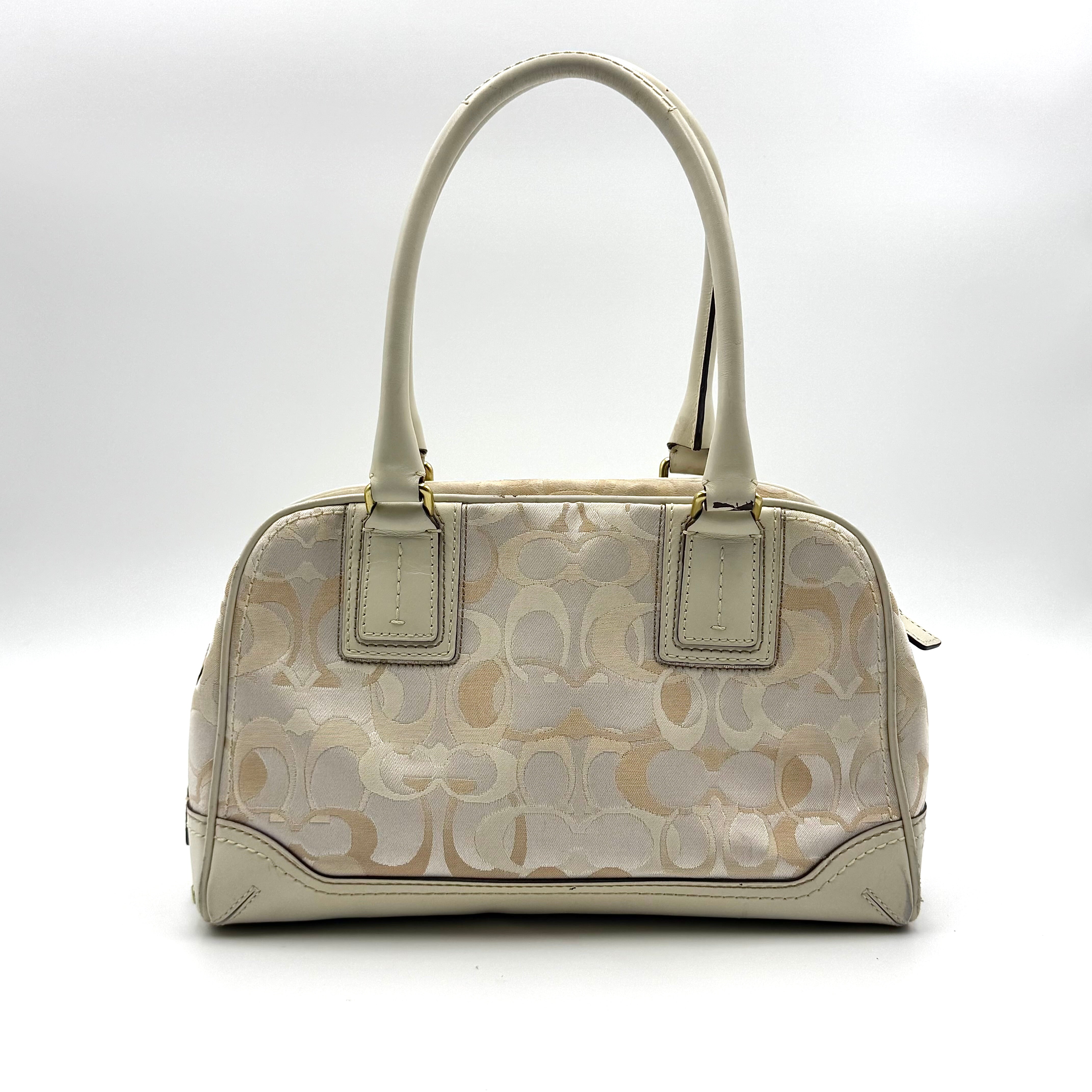 Coach Signature Canvas Satchel in ivory with dual rolled handles, monogram pattern and leather trim shown from the front against a clean background.