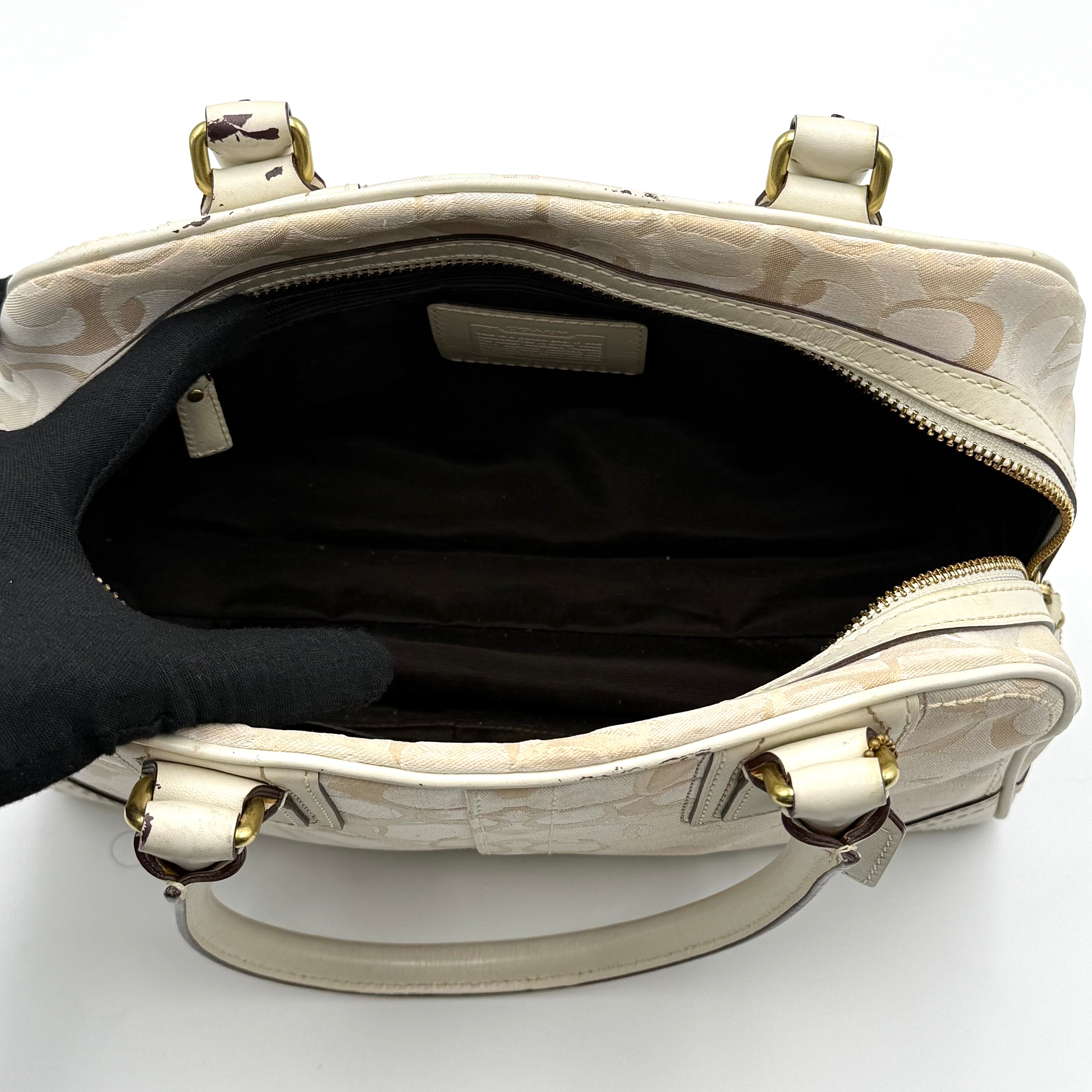 Coach Signature Canvas Satchel in ivory with dual rolled handles, monogram pattern and leather trim shown from the front against a clean background.