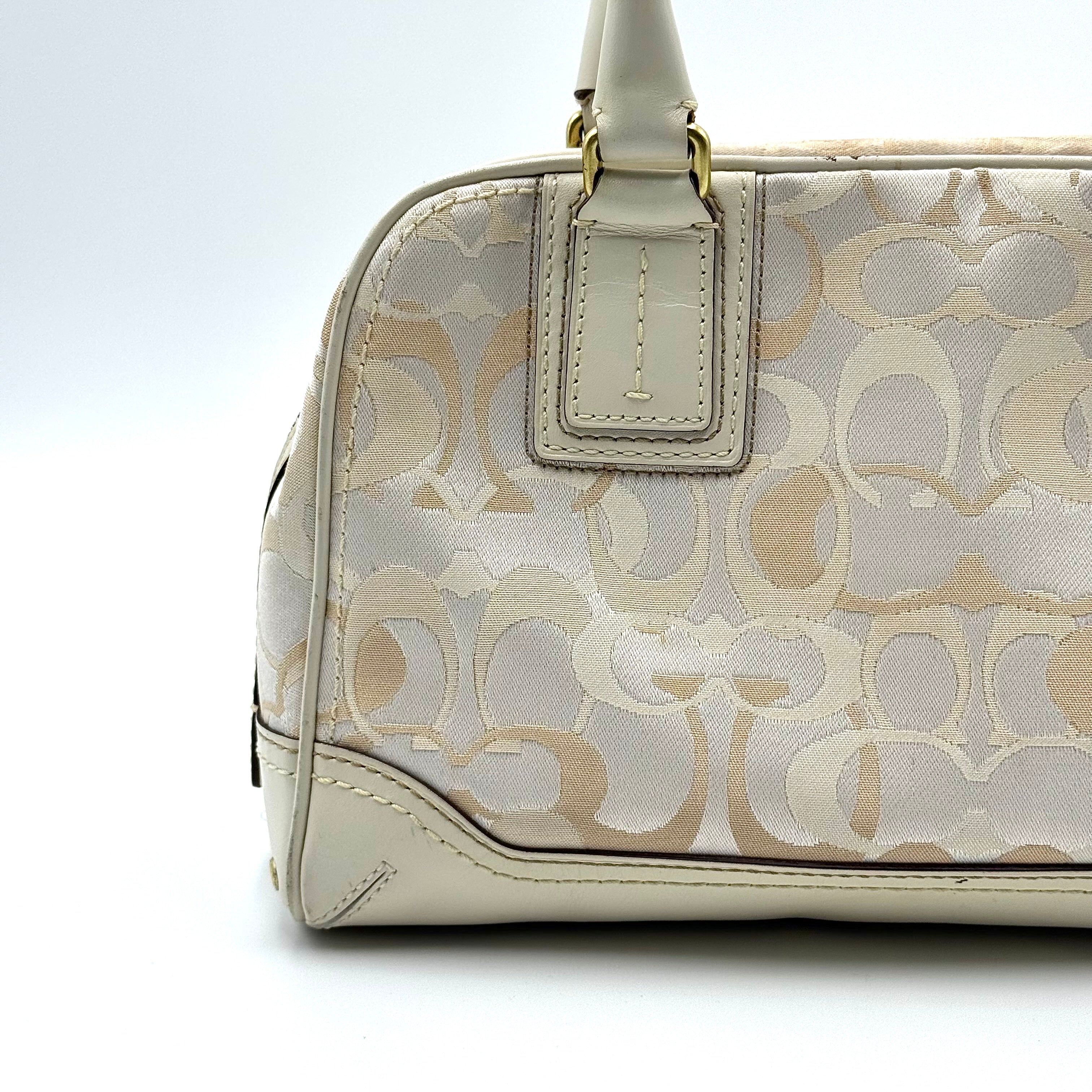 Coach Signature Canvas Satchel in ivory with dual rolled handles, monogram pattern and leather trim shown from the front against a clean background.