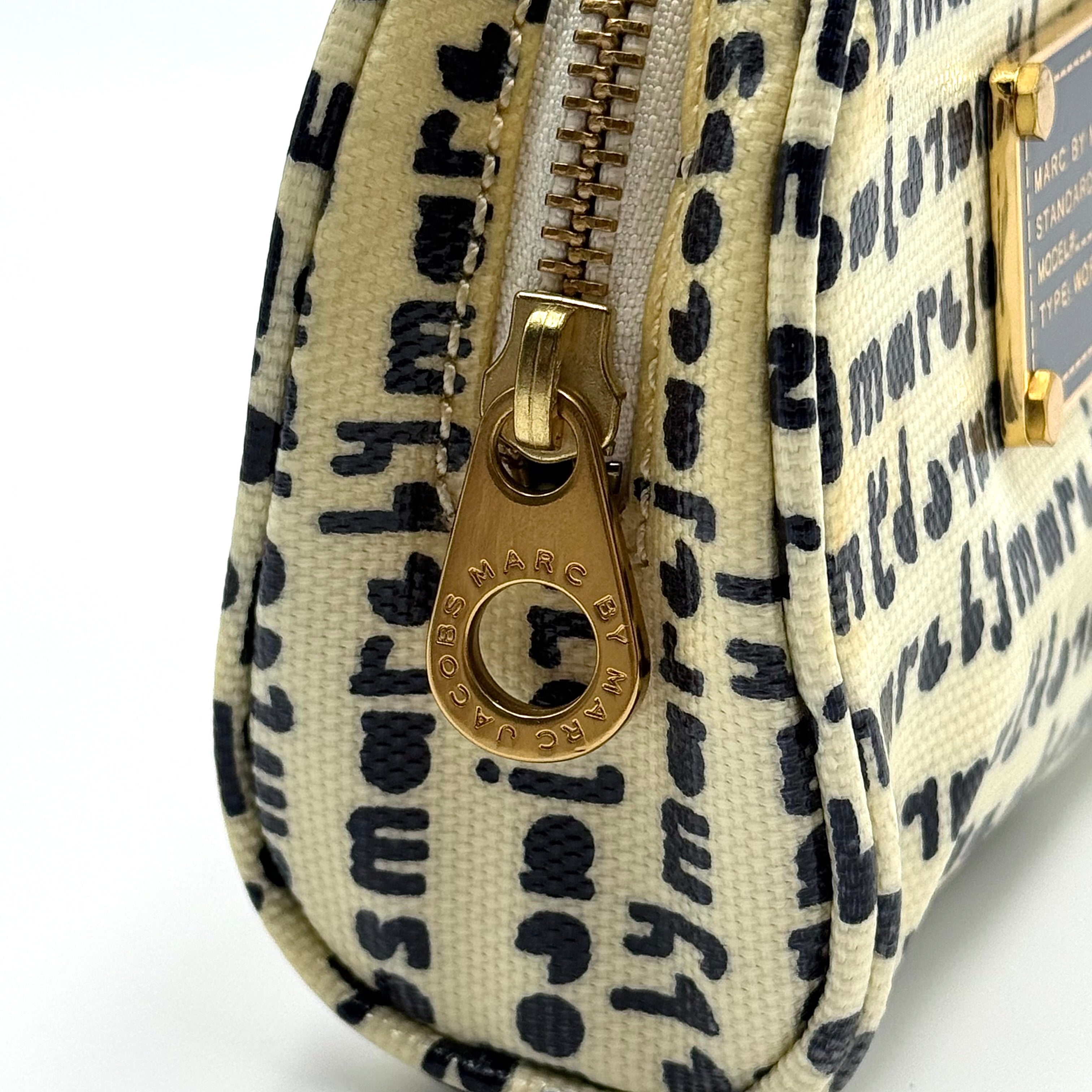 Marc Jacobs dome-shaped cosmetic case in cream coated canvas with navy script and gold hardware.