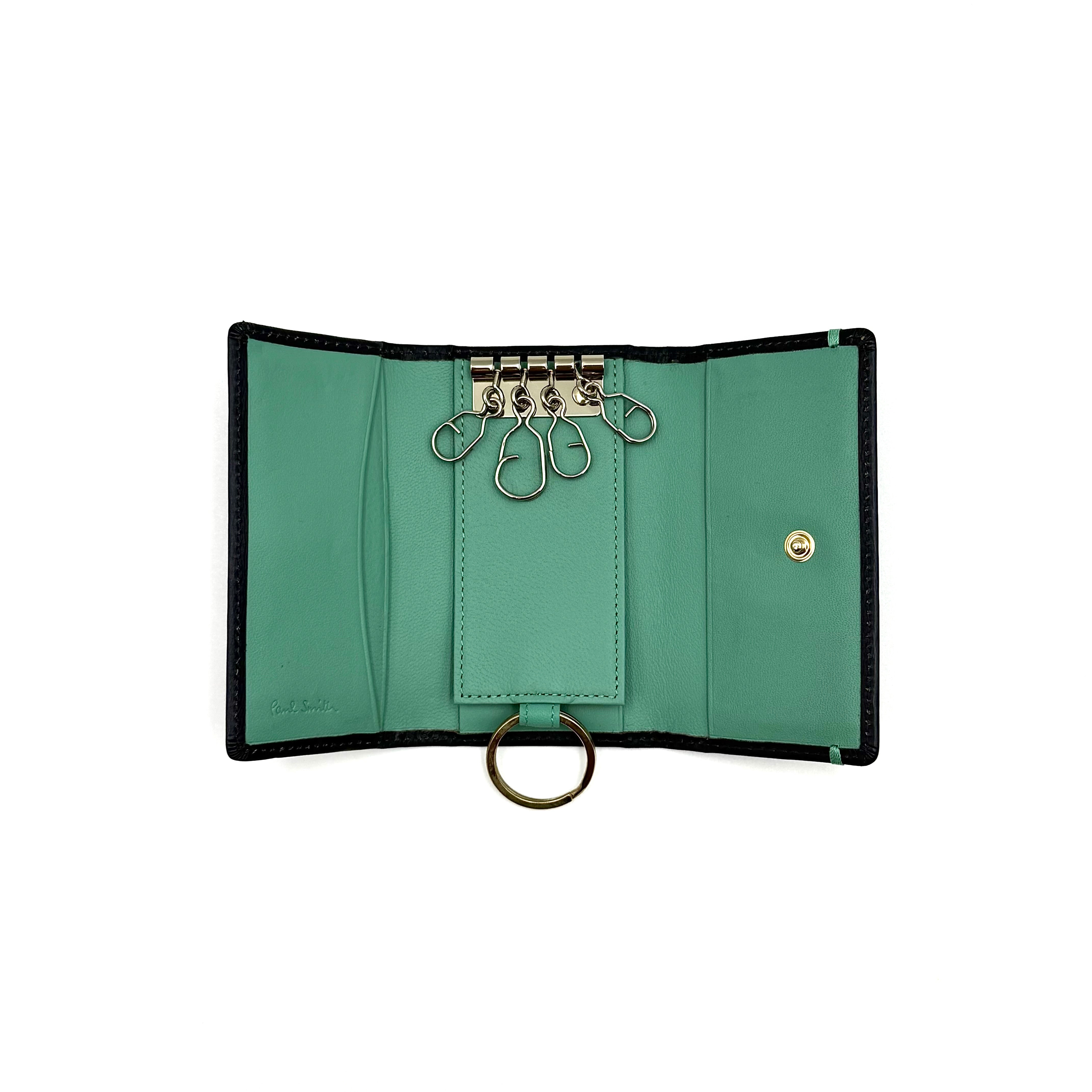 Paul Smith key case in grained black leather with Tiffany blue accents and silver logo, displayed on a white background.