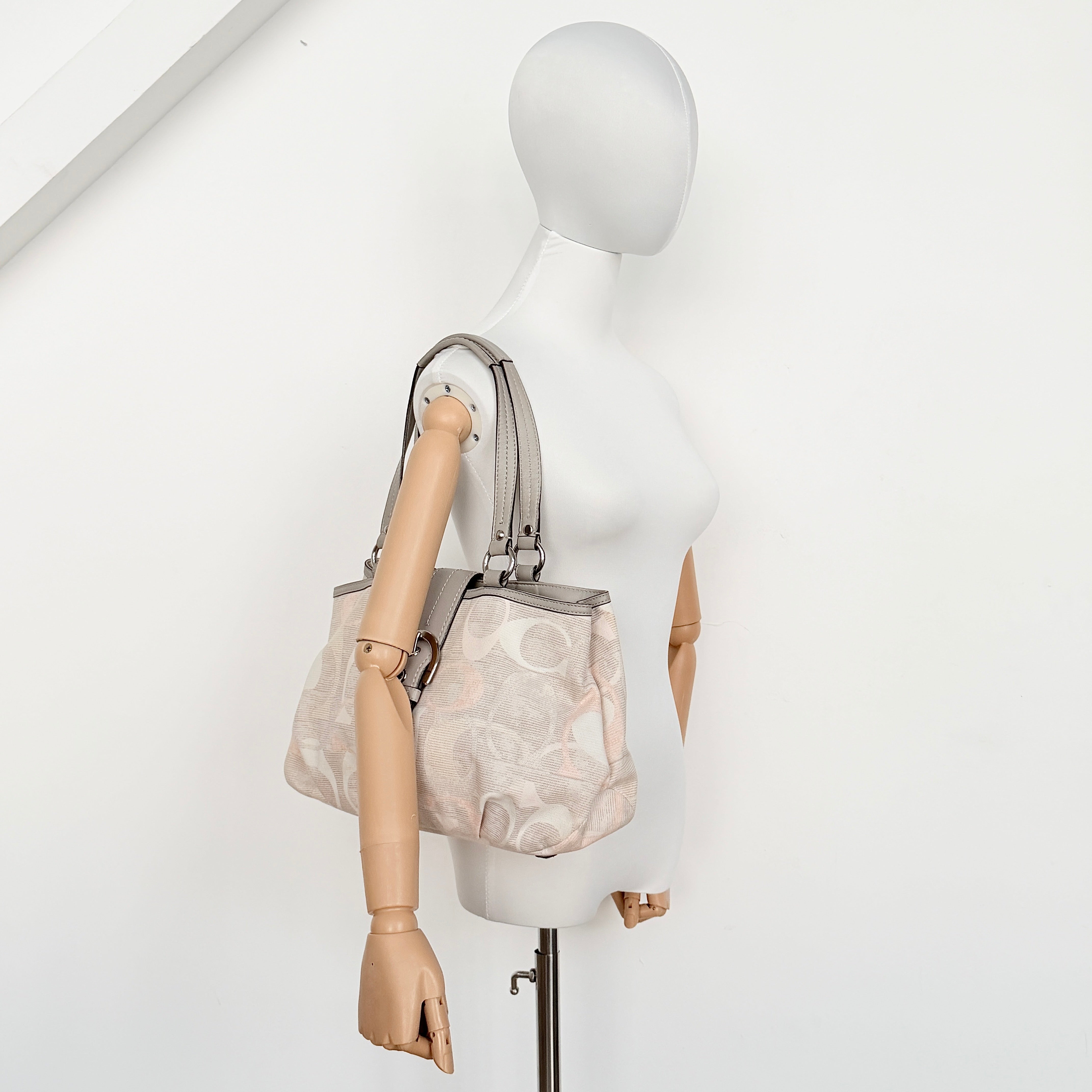 Coach Signature Optic Soho Shoulder Bag in grey and pink canvas with leather handles and buckle detail, shown against a white background.