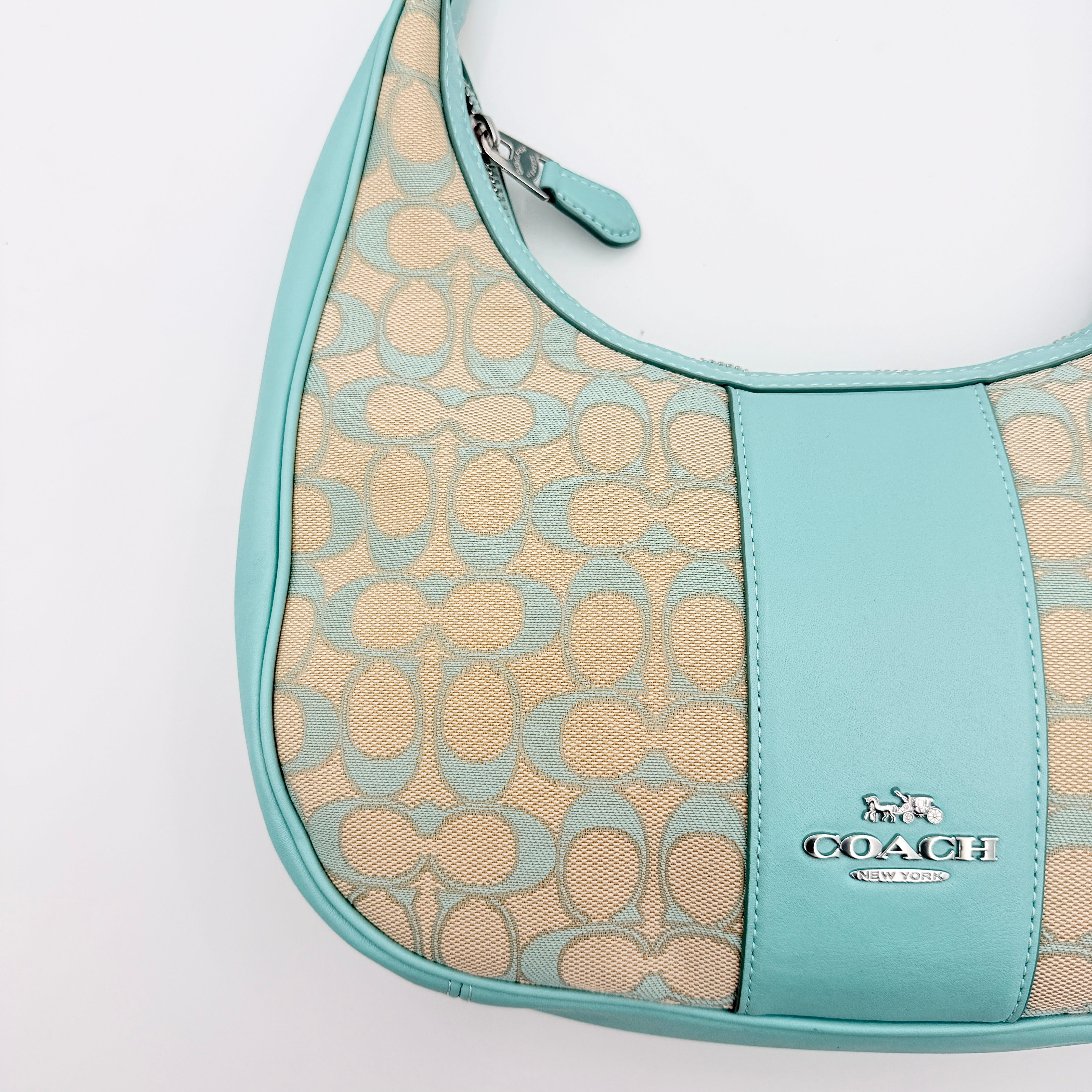 Coach Signature Carmen Shoulder Bag in beige and blue canvas with powder blue leather trim and silver hardware, photographed on white background.