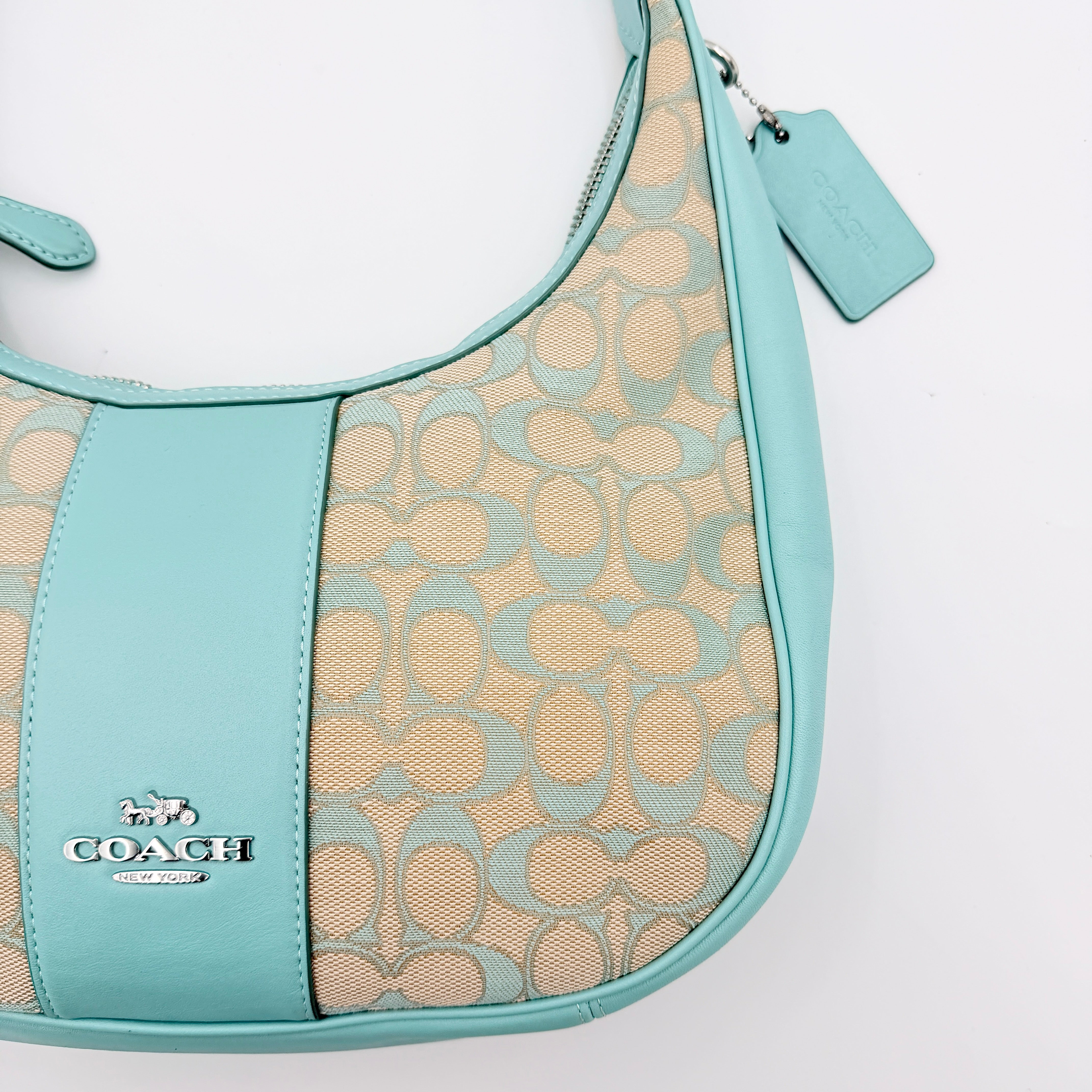 Coach Signature Carmen Shoulder Bag in beige and blue canvas with powder blue leather trim and silver hardware, photographed on white background.