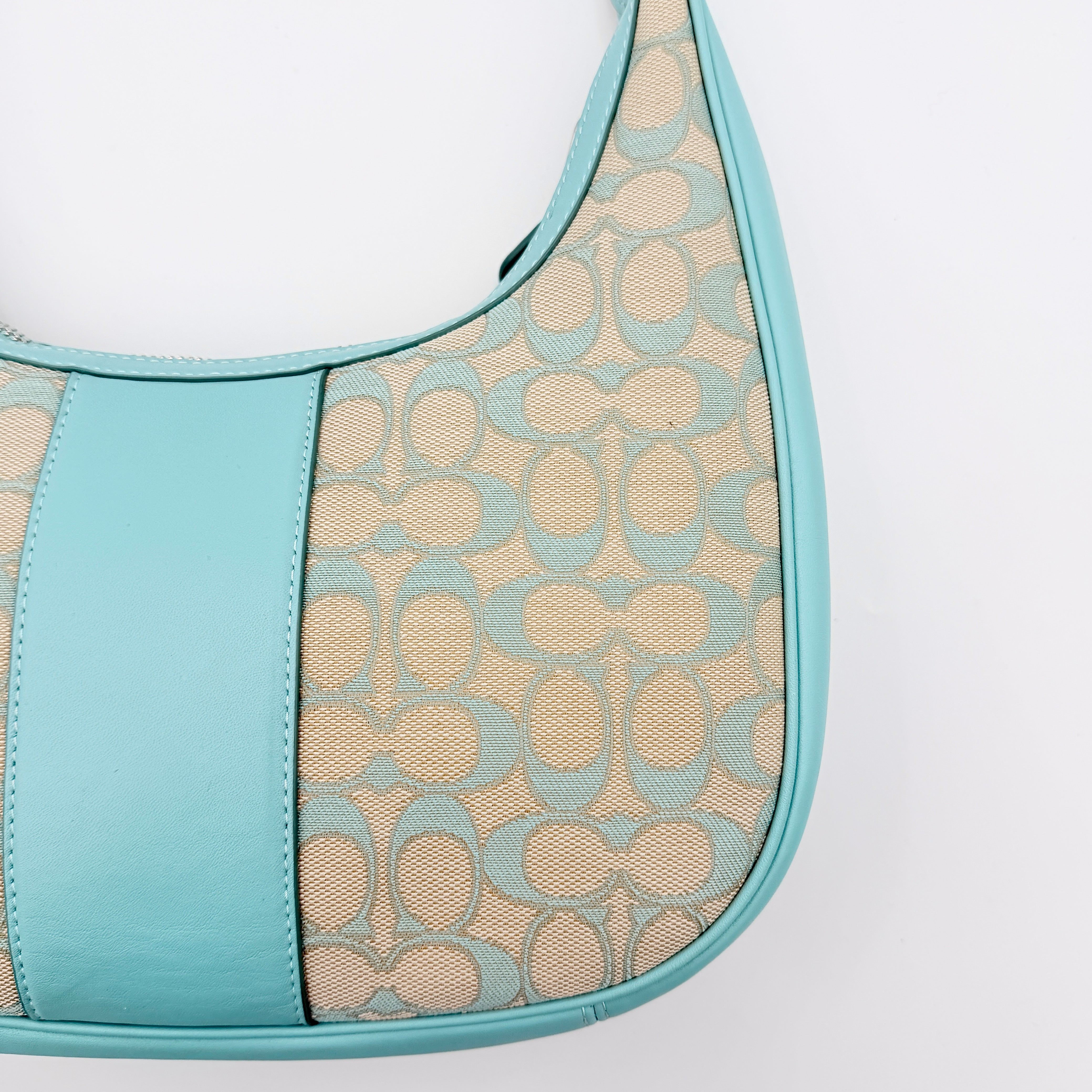 Coach Signature Carmen Shoulder Bag in beige and blue canvas with powder blue leather trim and silver hardware, photographed on white background.